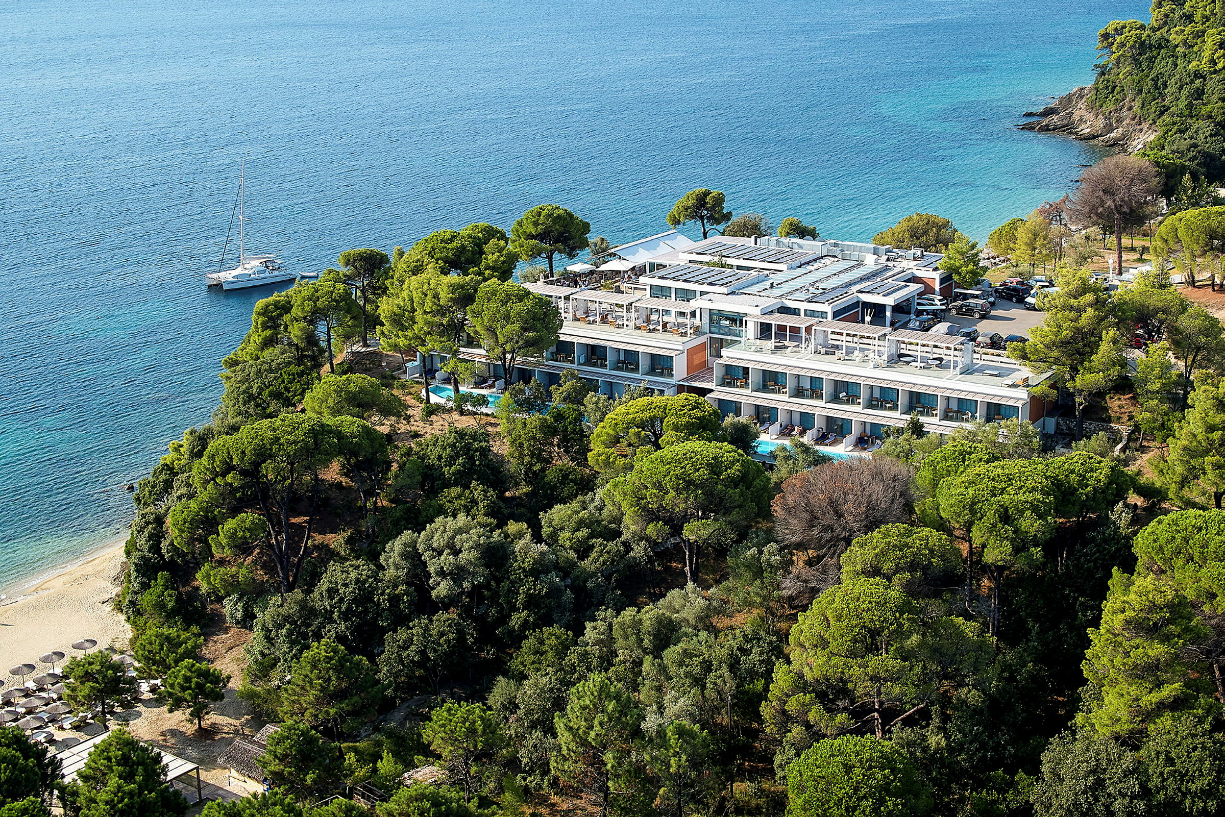 Et hotel omgivet af grønne områder med stranden og havet ved siden af. (AI-genereret tekst)