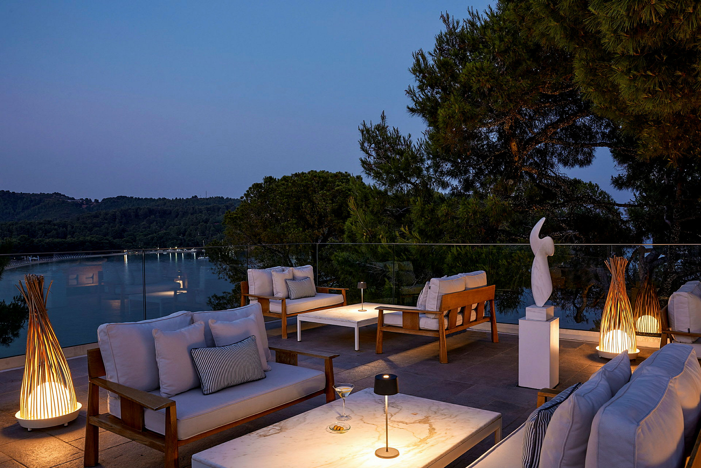 Udendørs lounge med sofaer, borde og dekorationer på en terrasse ved solnedgang. (AI-genereret tekst)