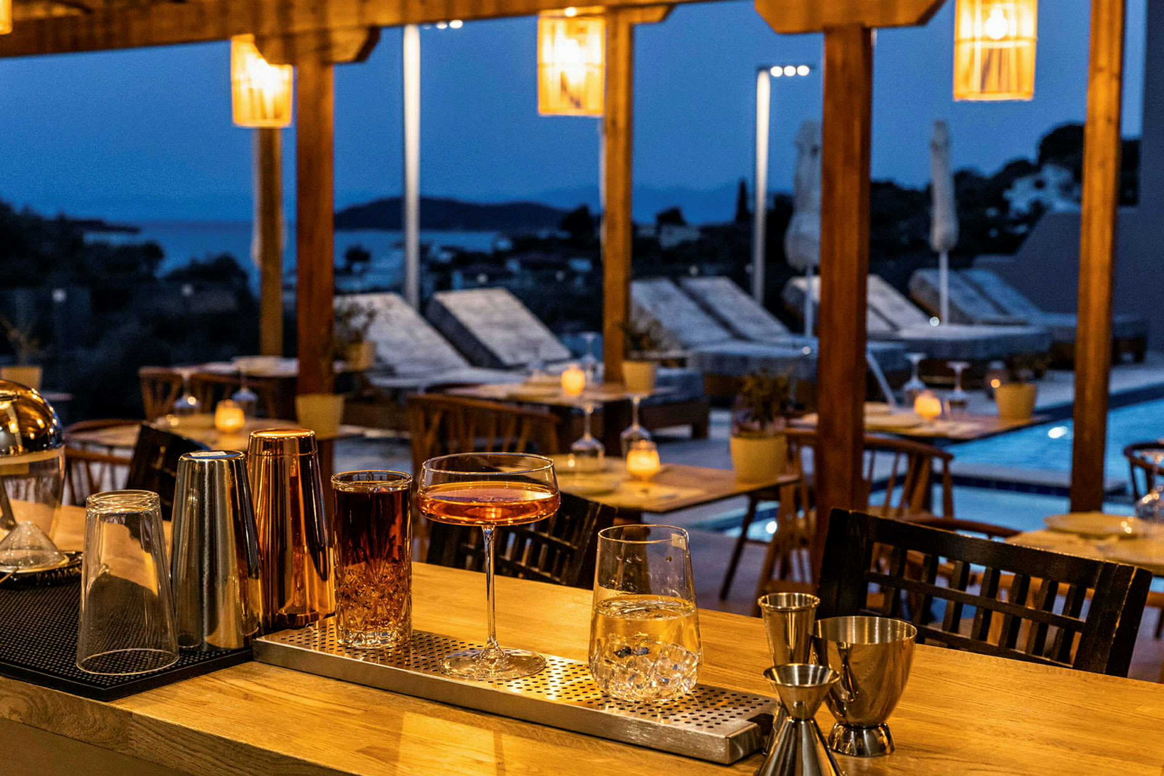 Cocktailglas og drinks står på en bardisk ved en aflyst terrasse. (AI-genereret tekst)