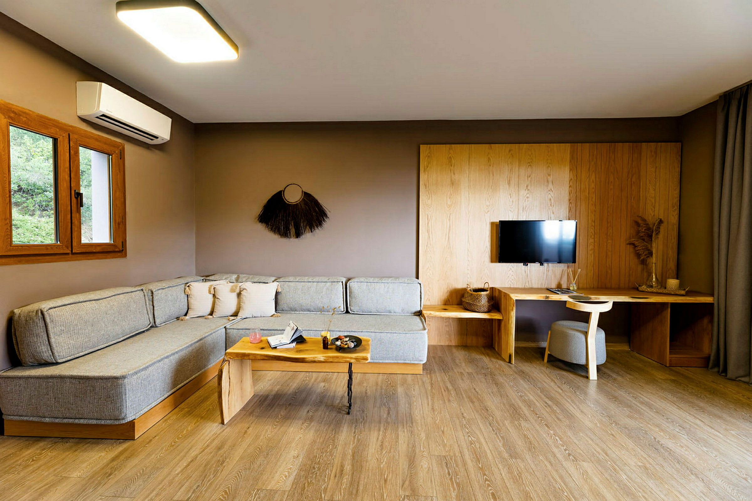 Moderne stue med hjørnesofa, sofabord, TV på væggen og skrivebord med stol. (AI-genereret tekst)