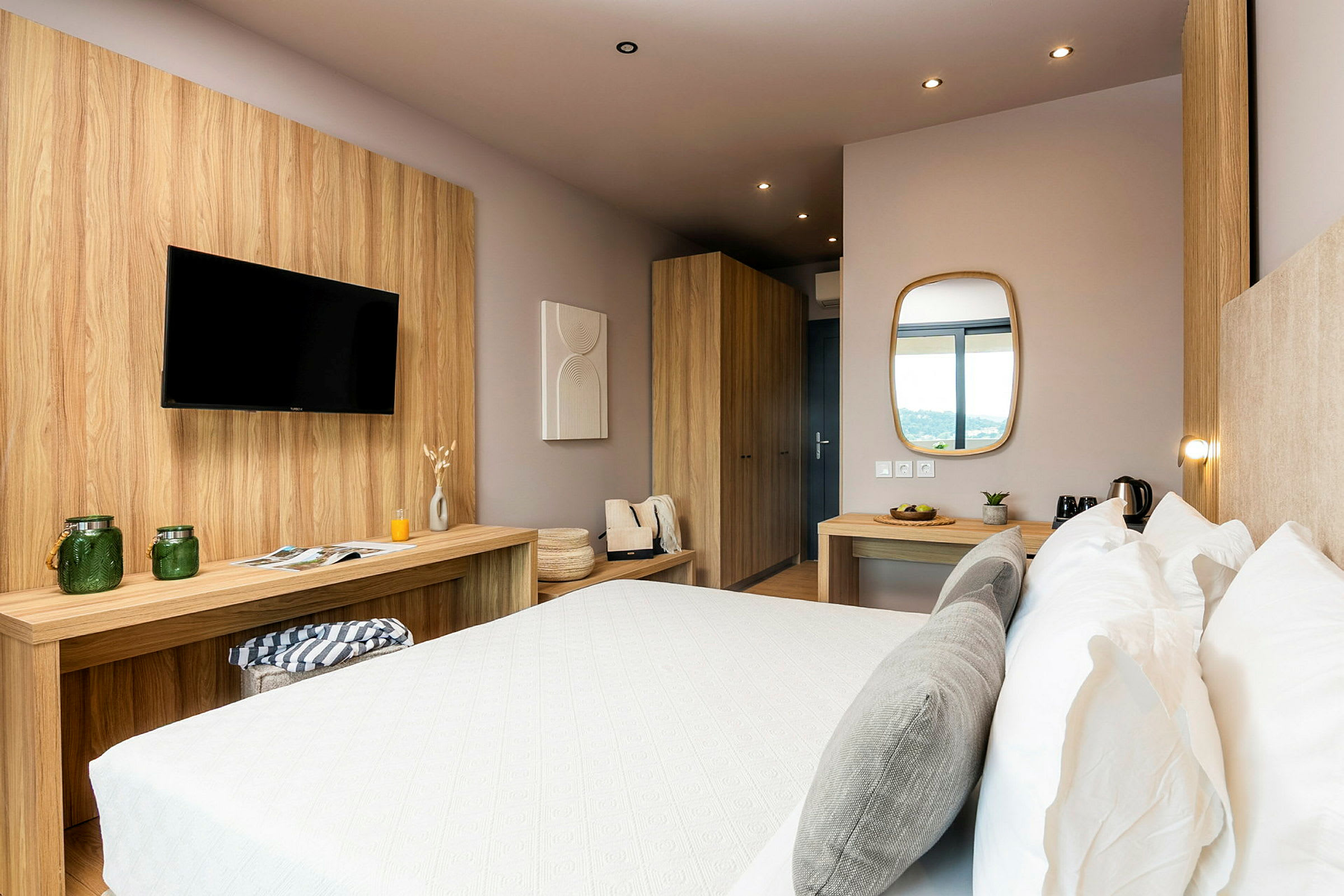 Et moderne hotelværelse med en dobbeltseng, træindretning, bord med spejl og TV. (AI-genereret tekst)