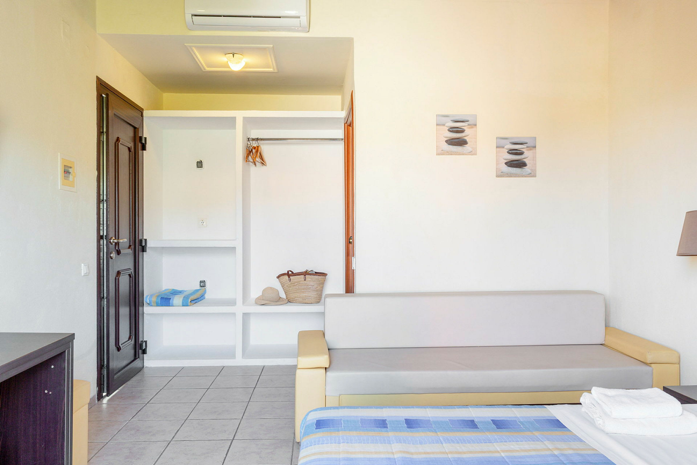Et hotelværelse med sofa, åben garderobe og seng. (AI-genereret tekst)
