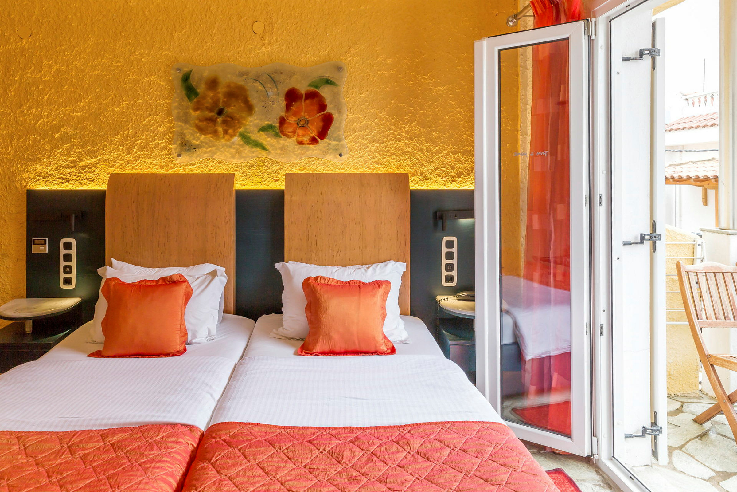 Hotelværelse med to enkeltsenge, orange pyntepuder og en altan. (AI-genereret tekst)