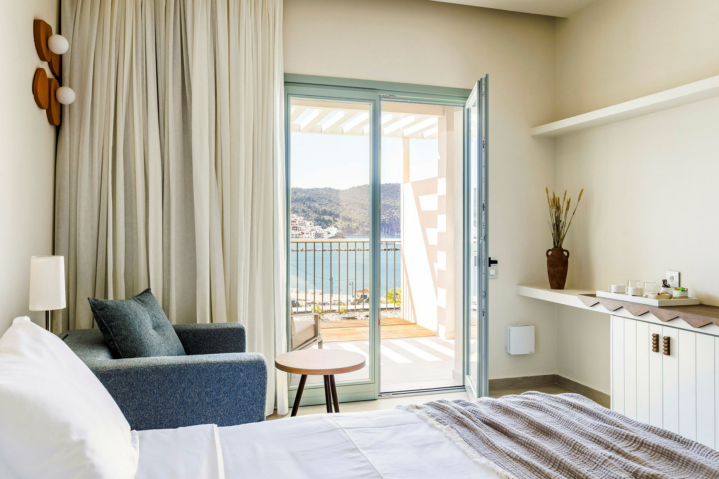 Hotelværelse med udsigt over havet fra en åben altandør. (AI-genereret tekst)