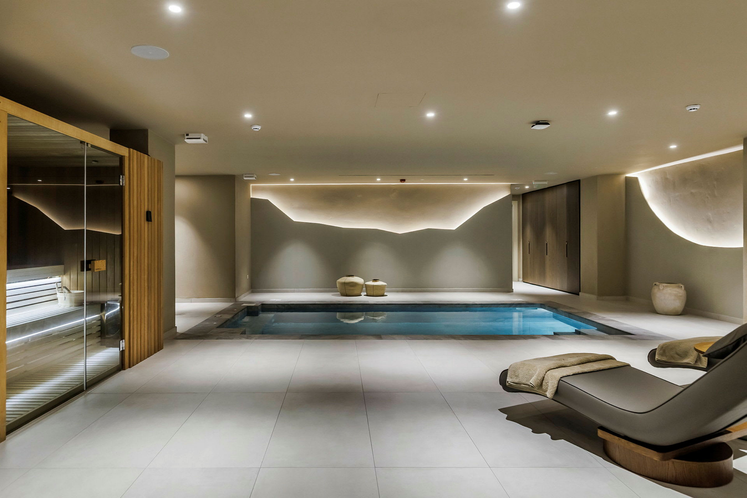 Et moderne indendørs spa med pool, liggestole og sauna. (AI-genereret tekst)