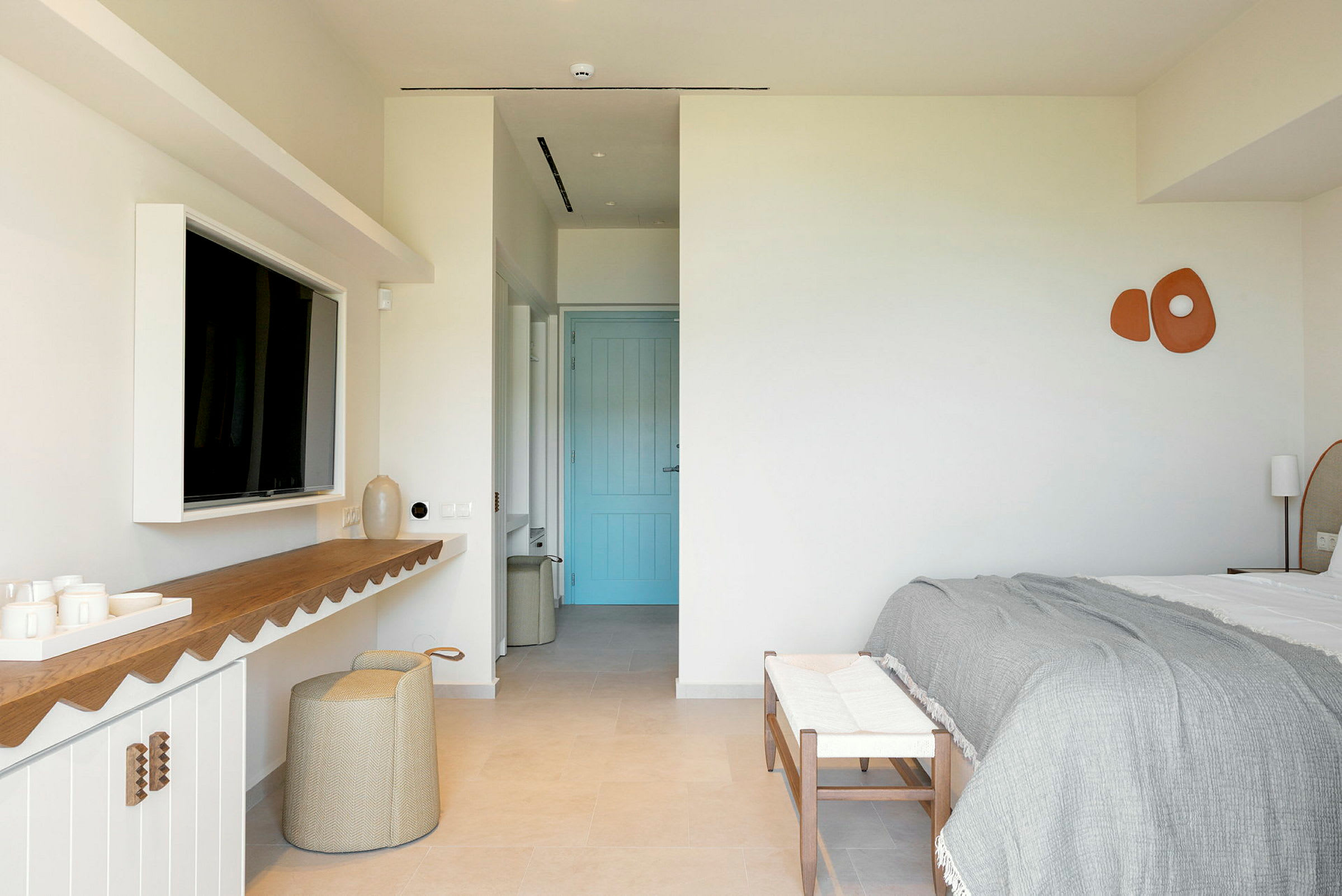 Et moderne hotelværelse med dobbeltseng, en blå dør og minimalistisk indretning. (AI-genereret tekst)