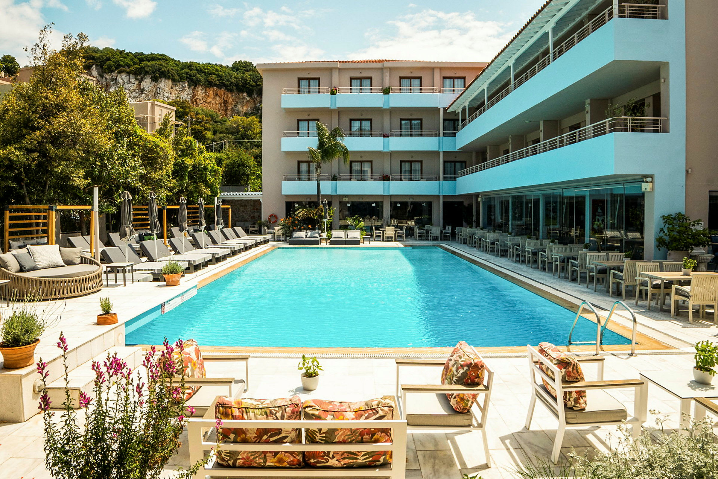 En udendørs pool omgivet af liggestole og parasoller ved et moderne hotel. (AI-genereret tekst)