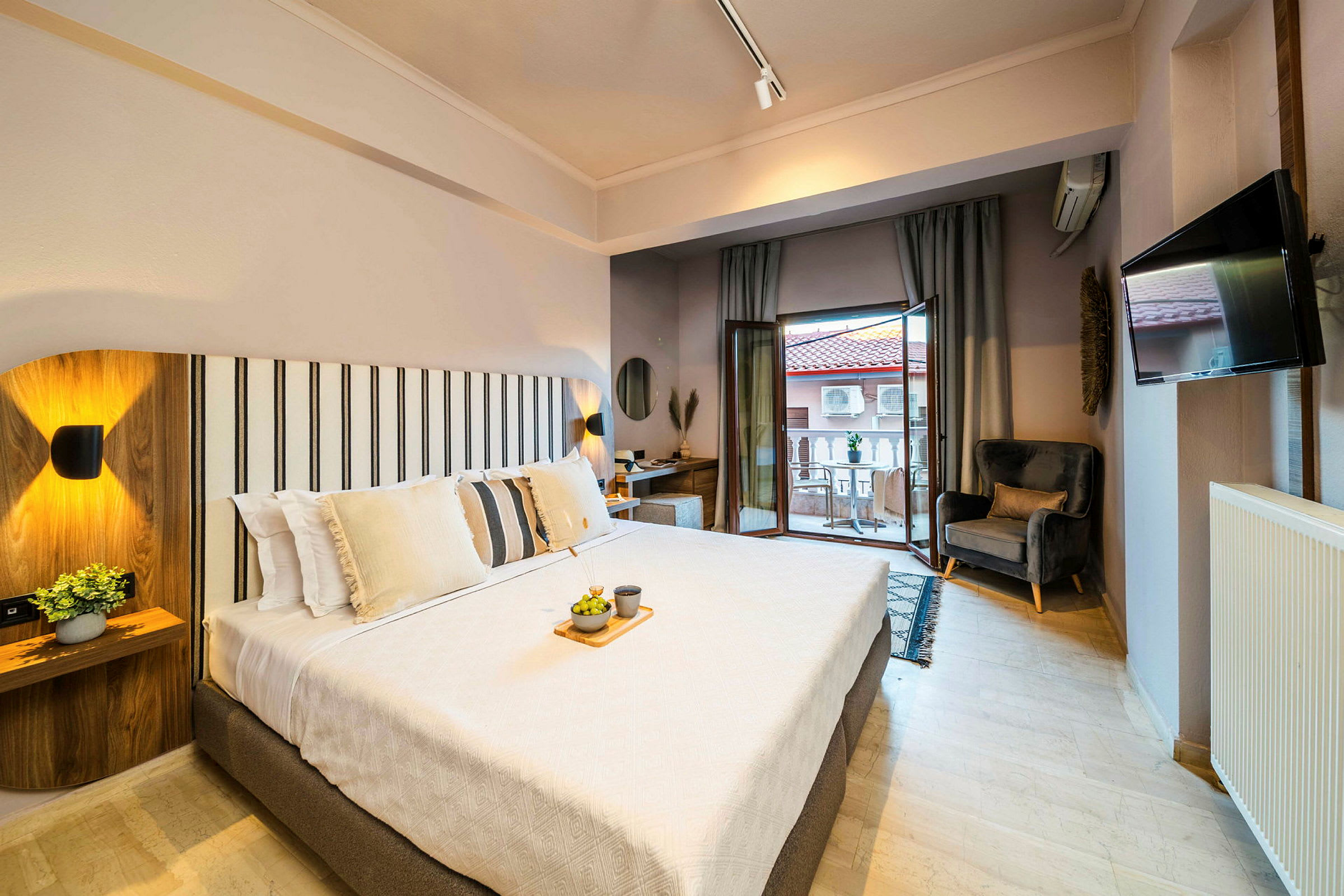 Et lyst og moderne hotelværelse med en stor seng, siddeområde og balkon. (AI-genereret tekst)