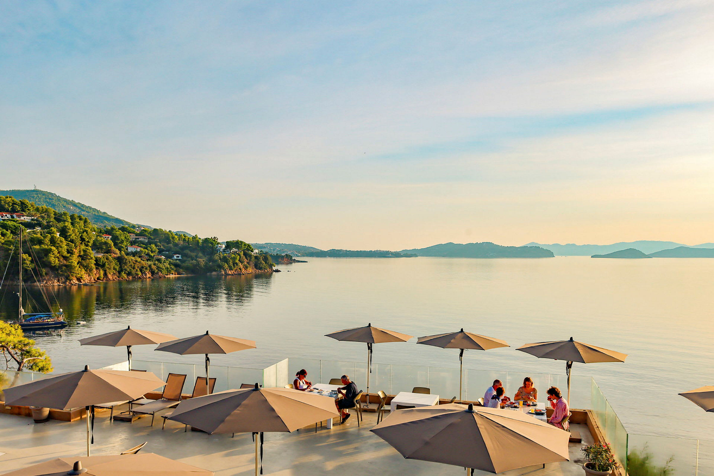 Udsigt over havet med en terrasse, hvor parasoller og siddegrupper er synlige. (AI-genereret tekst)