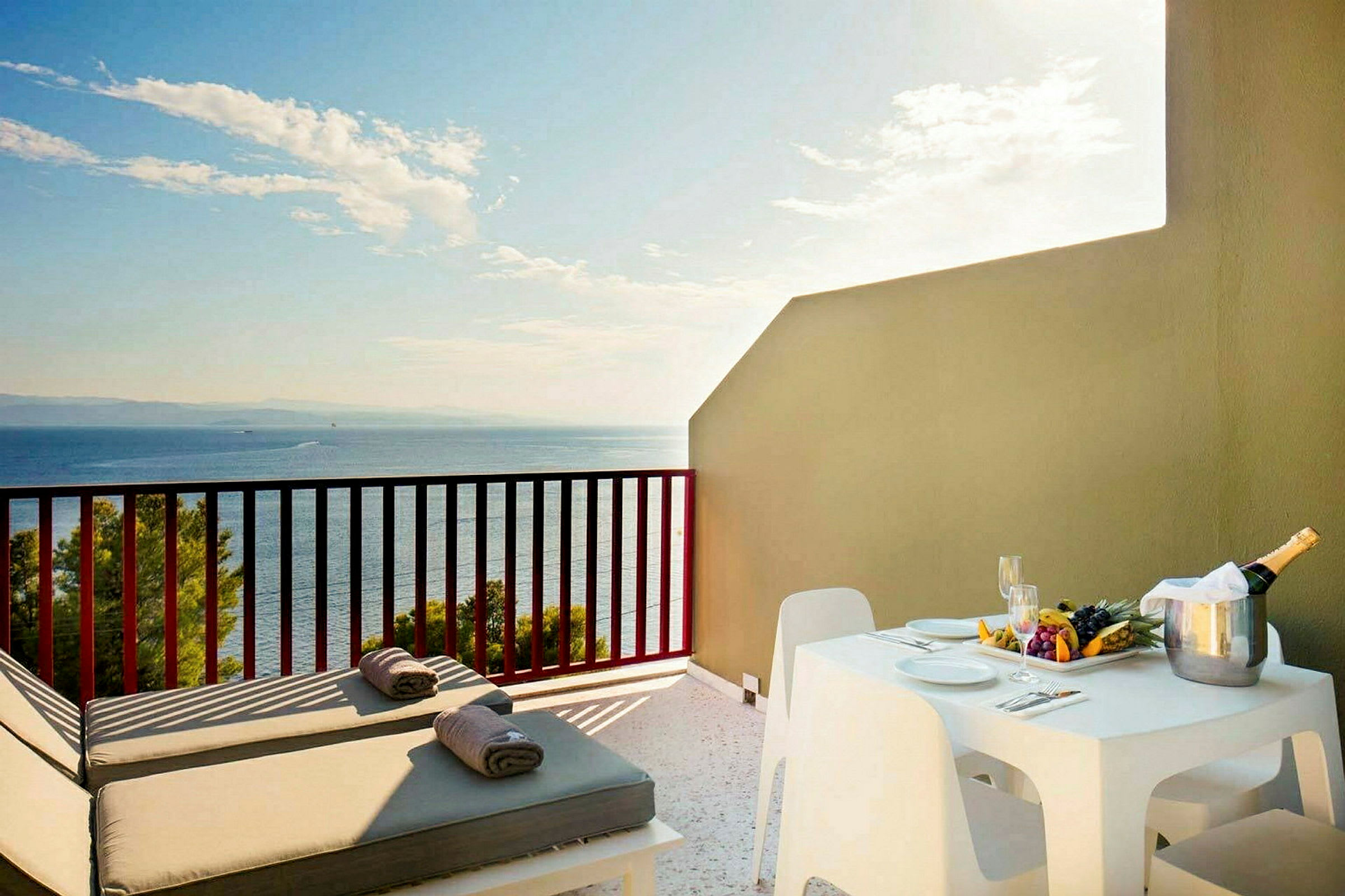 En terrasse med solsenge, bord og stole samt udsigt over havet. (AI-genereret tekst)
