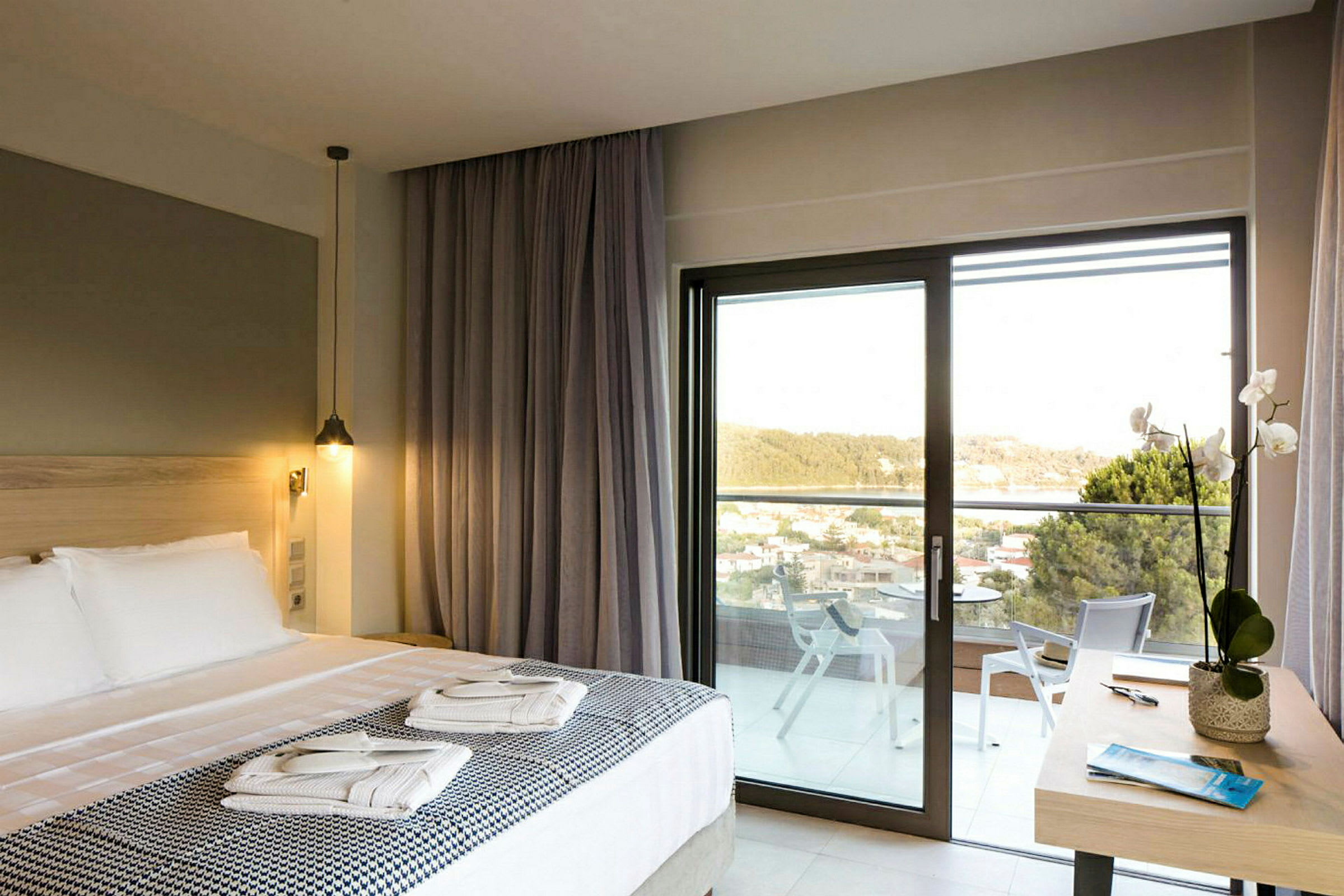 Hotelværelse med dobbeltseng, balkon og udsigt over grønne områder. (AI-genereret tekst)
