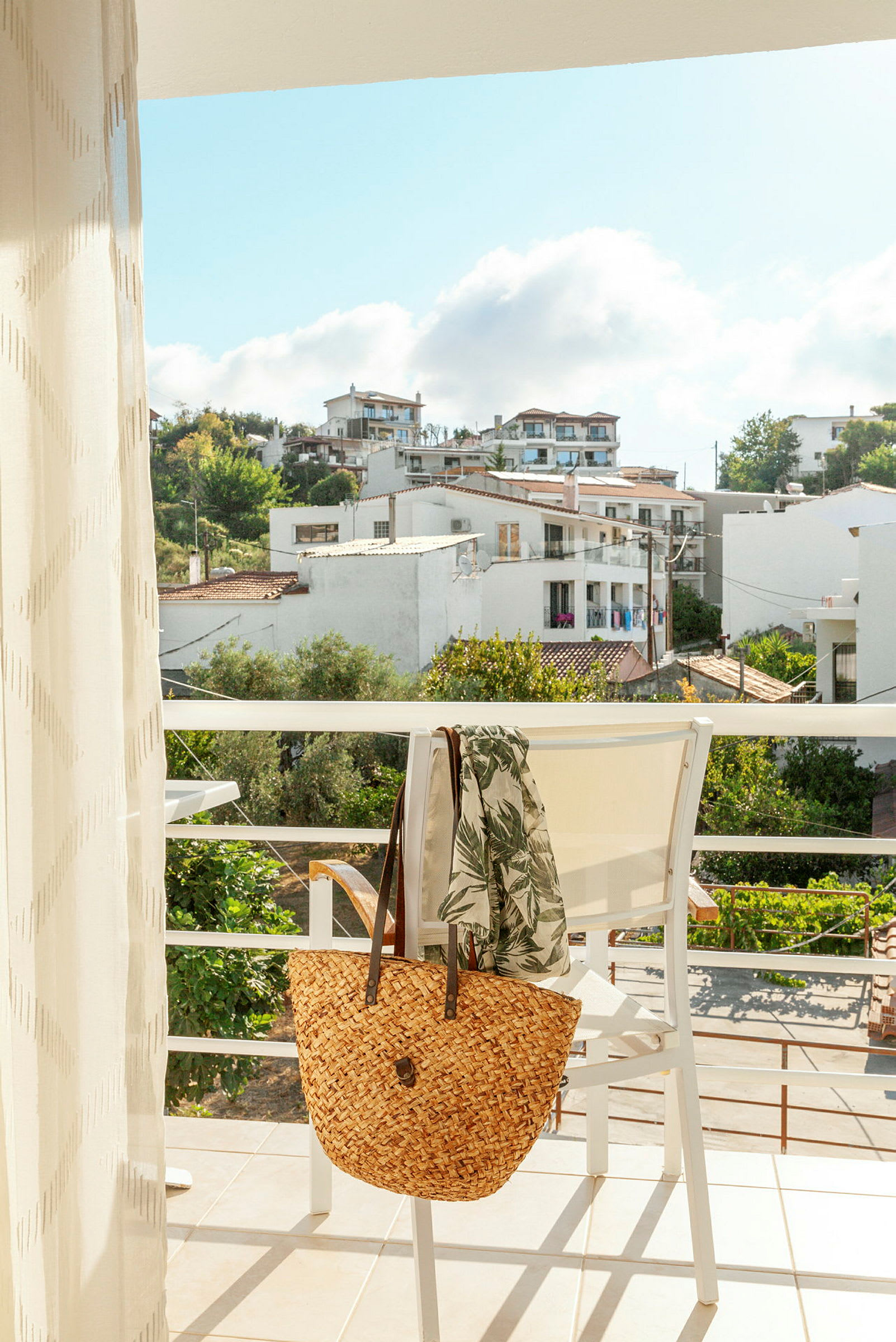 Udsigt fra en balkon mod de omkringliggende bygninger og frodigt grønt. (AI-genereret tekst)