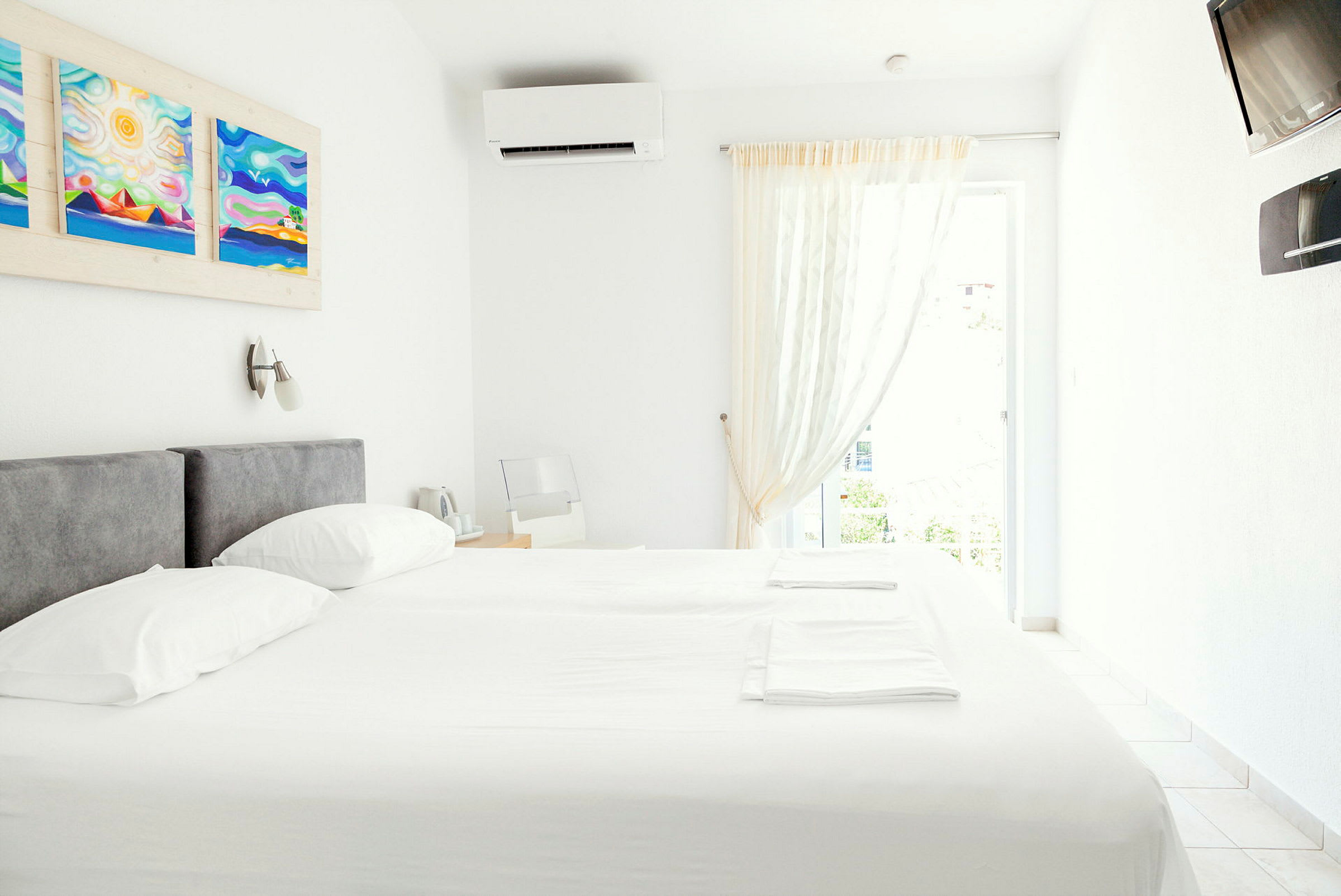 Et lyst og moderne indrettet hotelværelse med en dobbeltseng, vægkunst og aircondition. (AI-genereret tekst)