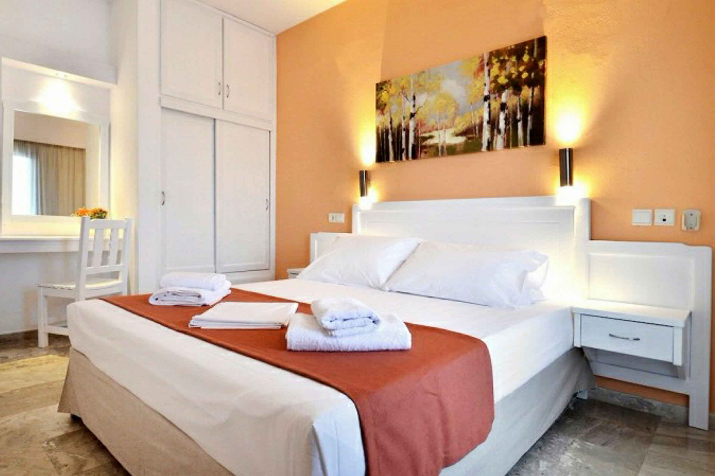 Hotelværelse med en dobbeltseng, natbord, garderobe og et maleri på væggen. (AI-genereret tekst)