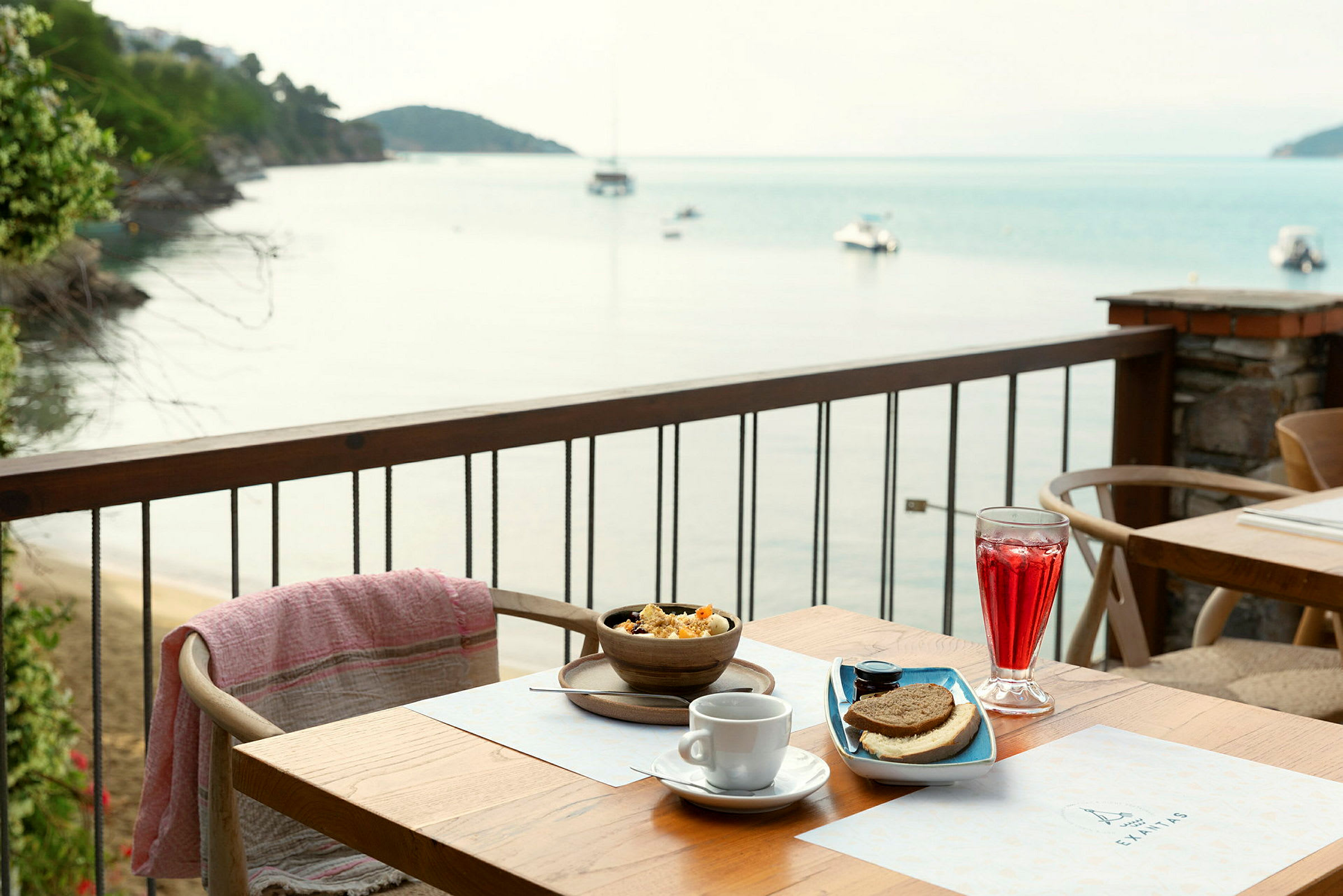 Morgenmad serveret på en terrasse med udsigt over havet og både. (AI-genereret tekst)
