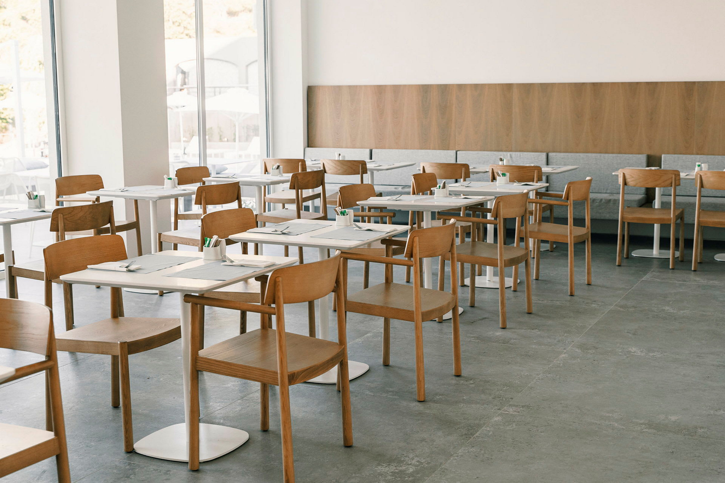 Restaurant med moderne træstole og dækkede borde. (AI-genereret tekst)