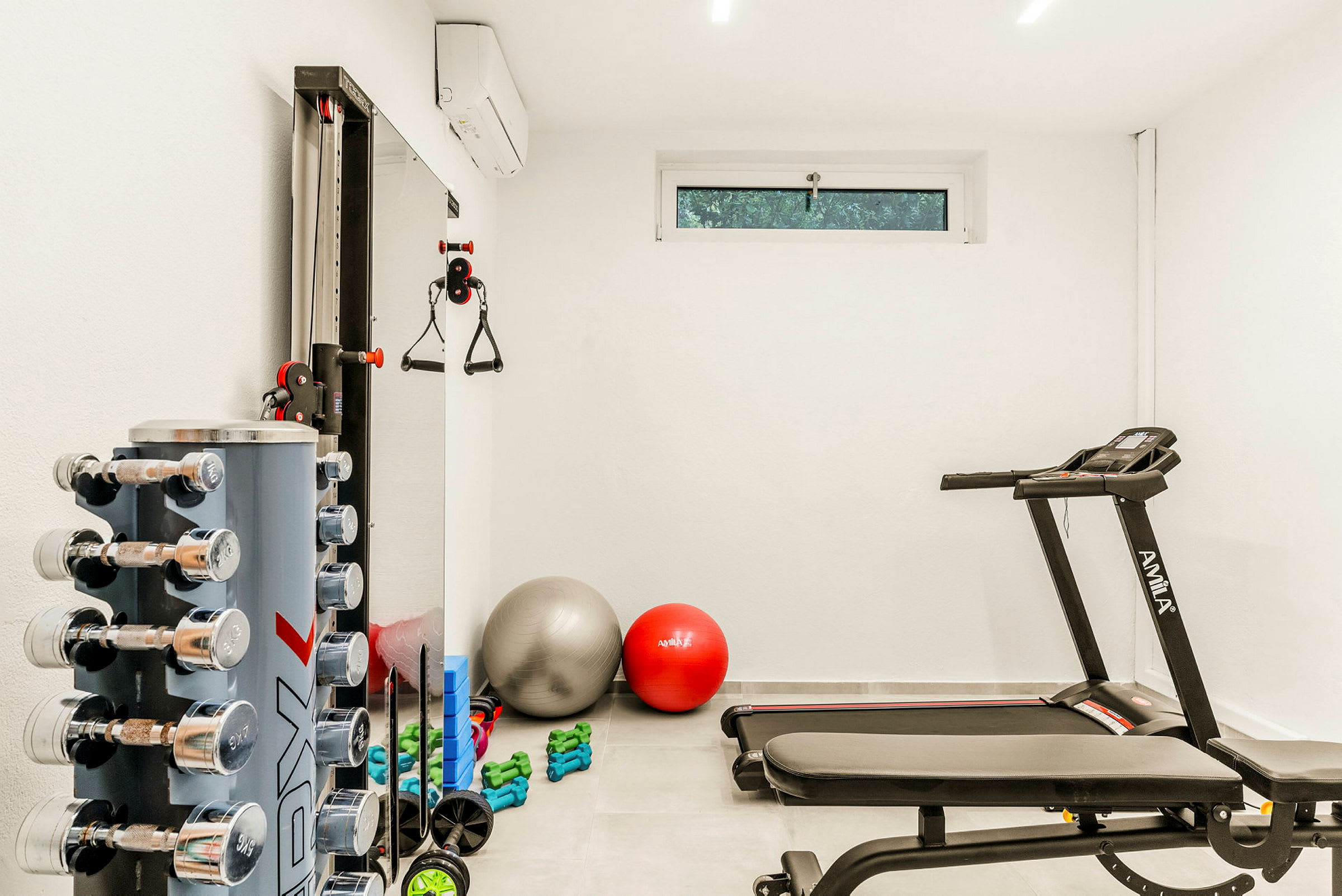 Et fitnessrum med træningsudstyr, herunder håndvægte, yoga bolde og en løbebånd. (AI-genereret tekst)