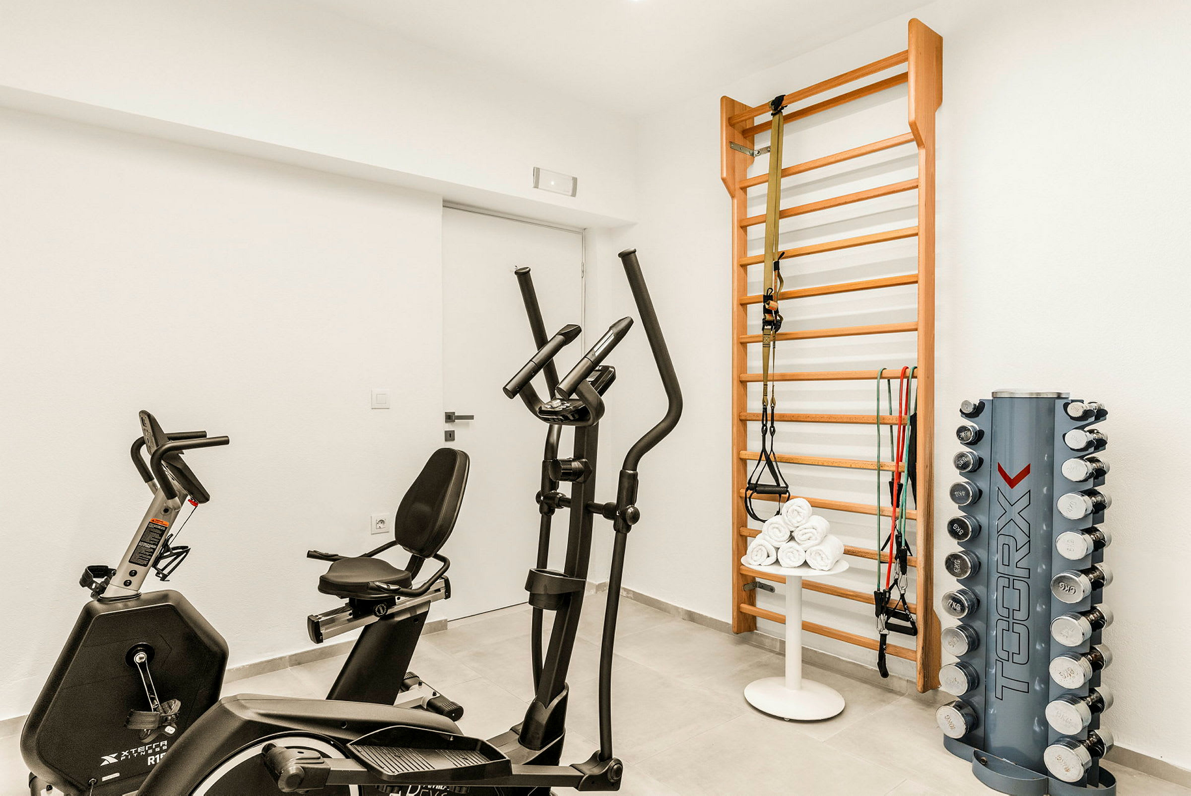 Et fitnessrum med motionscykel, crosstrainer, ribbevægs og håndvægte. (AI-genereret tekst)