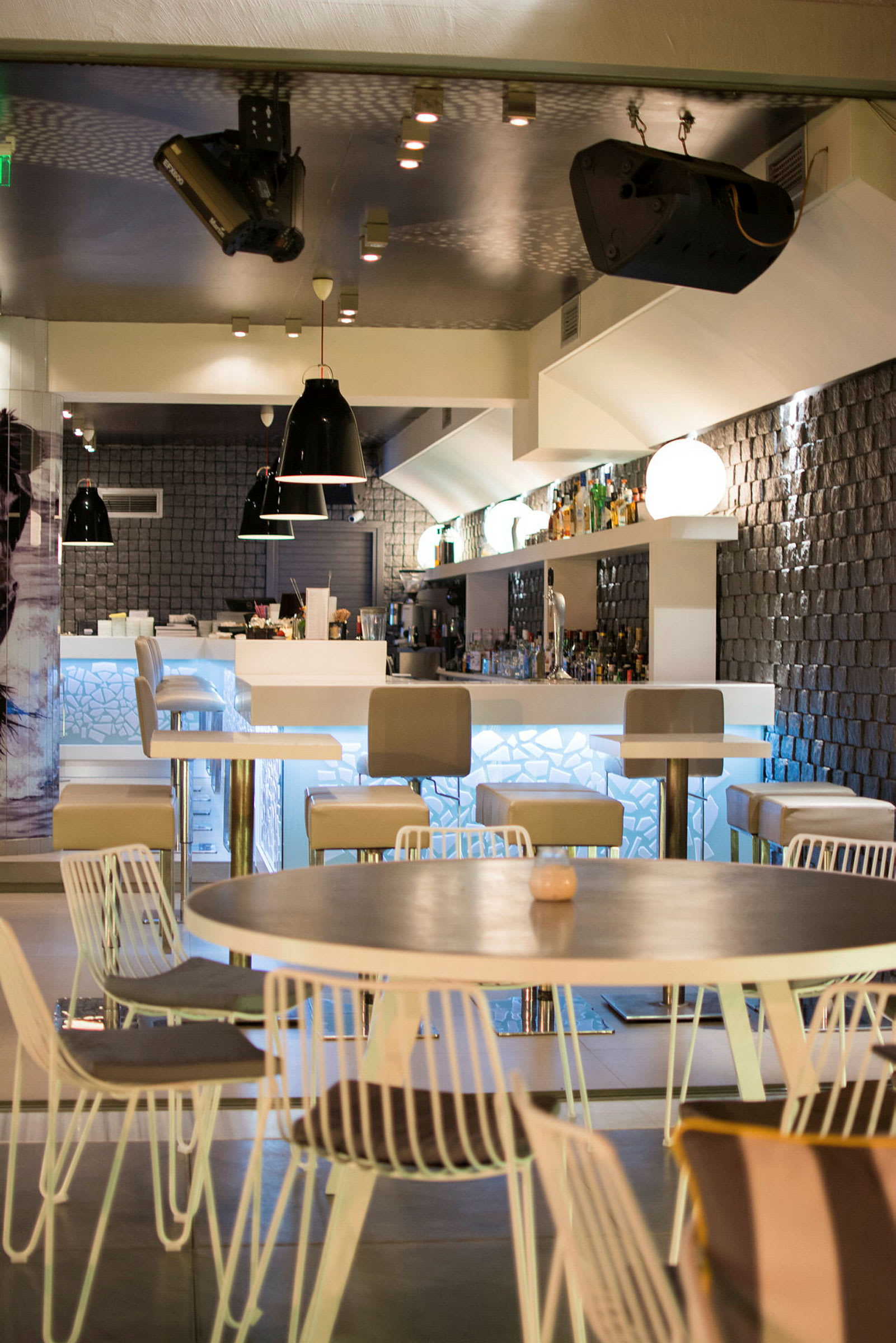 En moderne bar med høje stole, borde og et oplyst serveringsområde. (AI-genereret tekst)