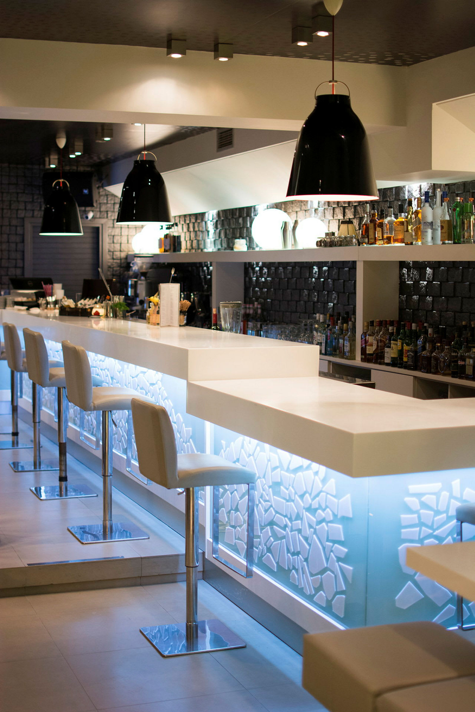 En moderne bar med hvide stole og en lyssat bardisk. (AI-genereret tekst)