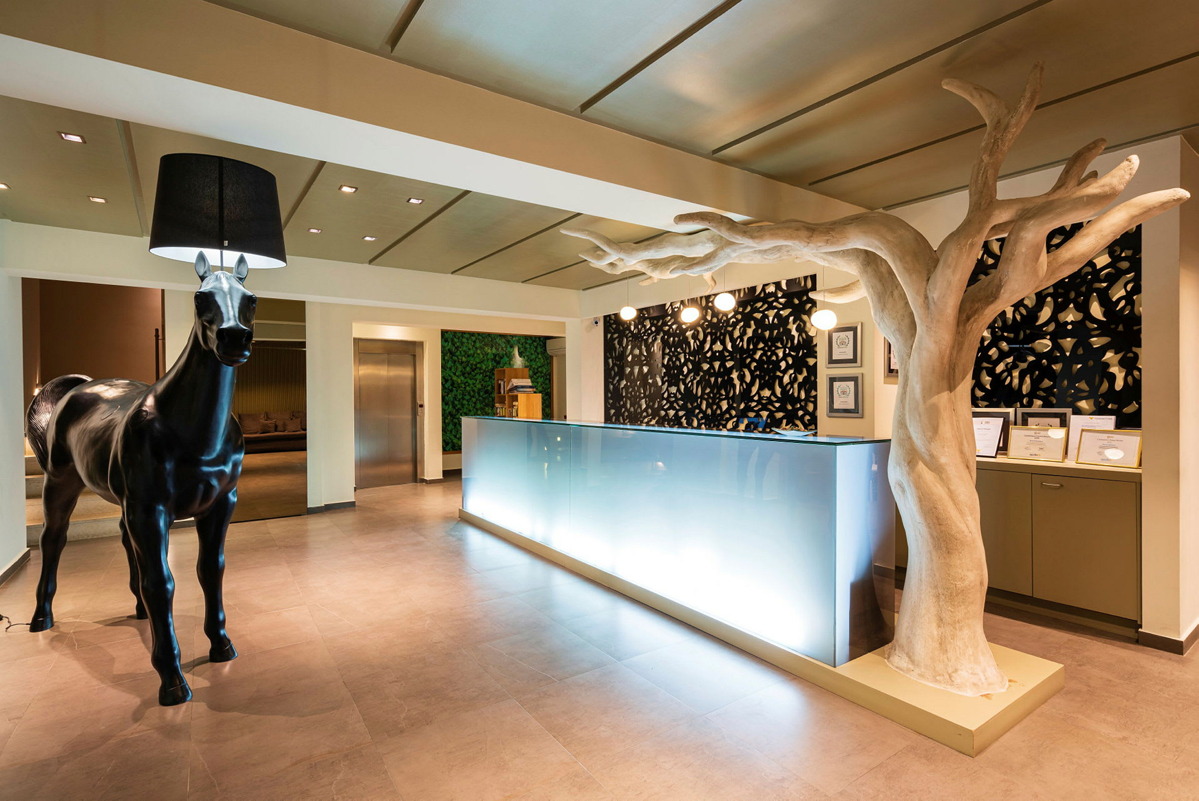 Moderne hotelreception med skulptur af en hest og et træ indendørs. (AI-genereret tekst)