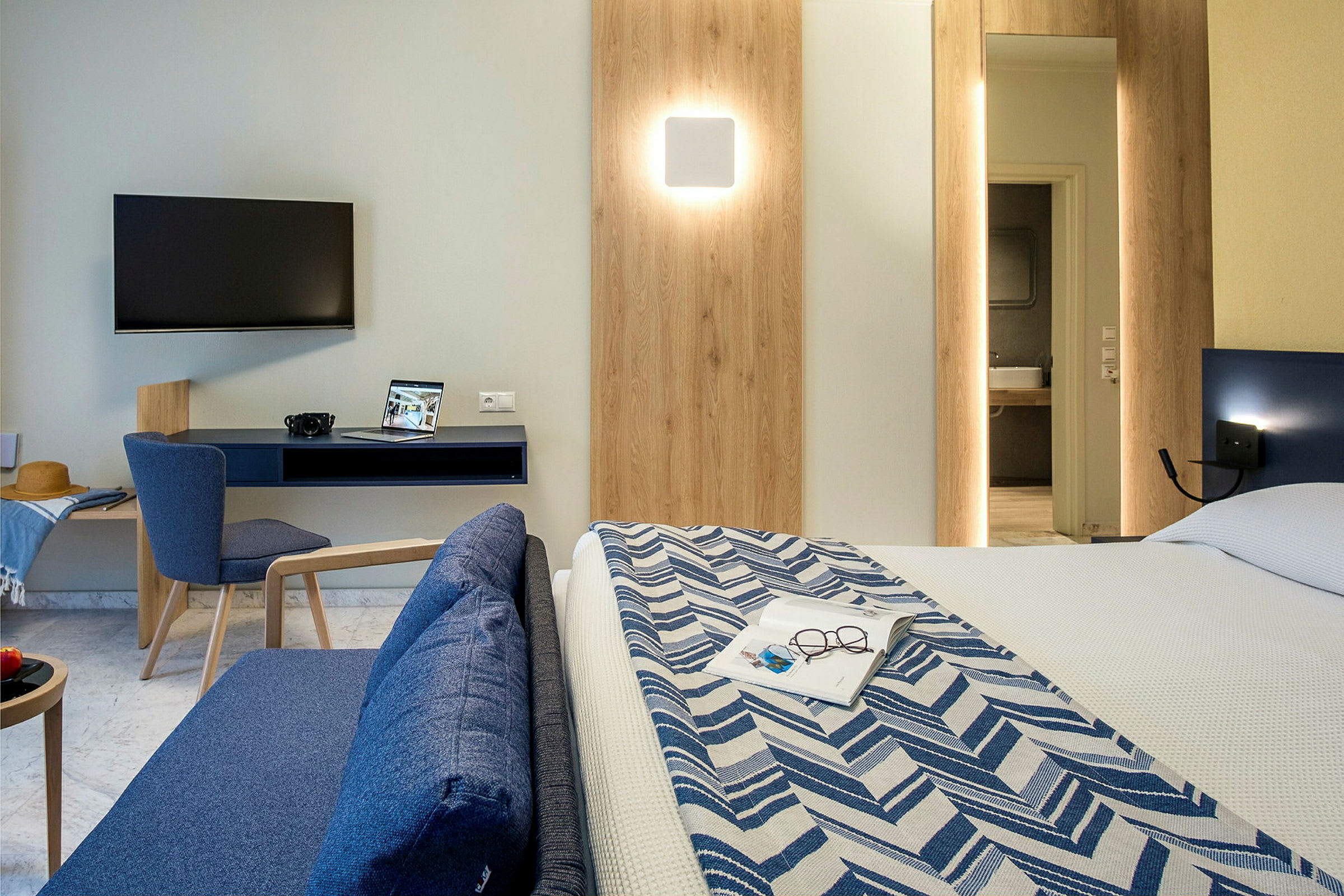 Moderne hotelværelse med tv, skrivebord, sofa og seng. (AI-genereret tekst)