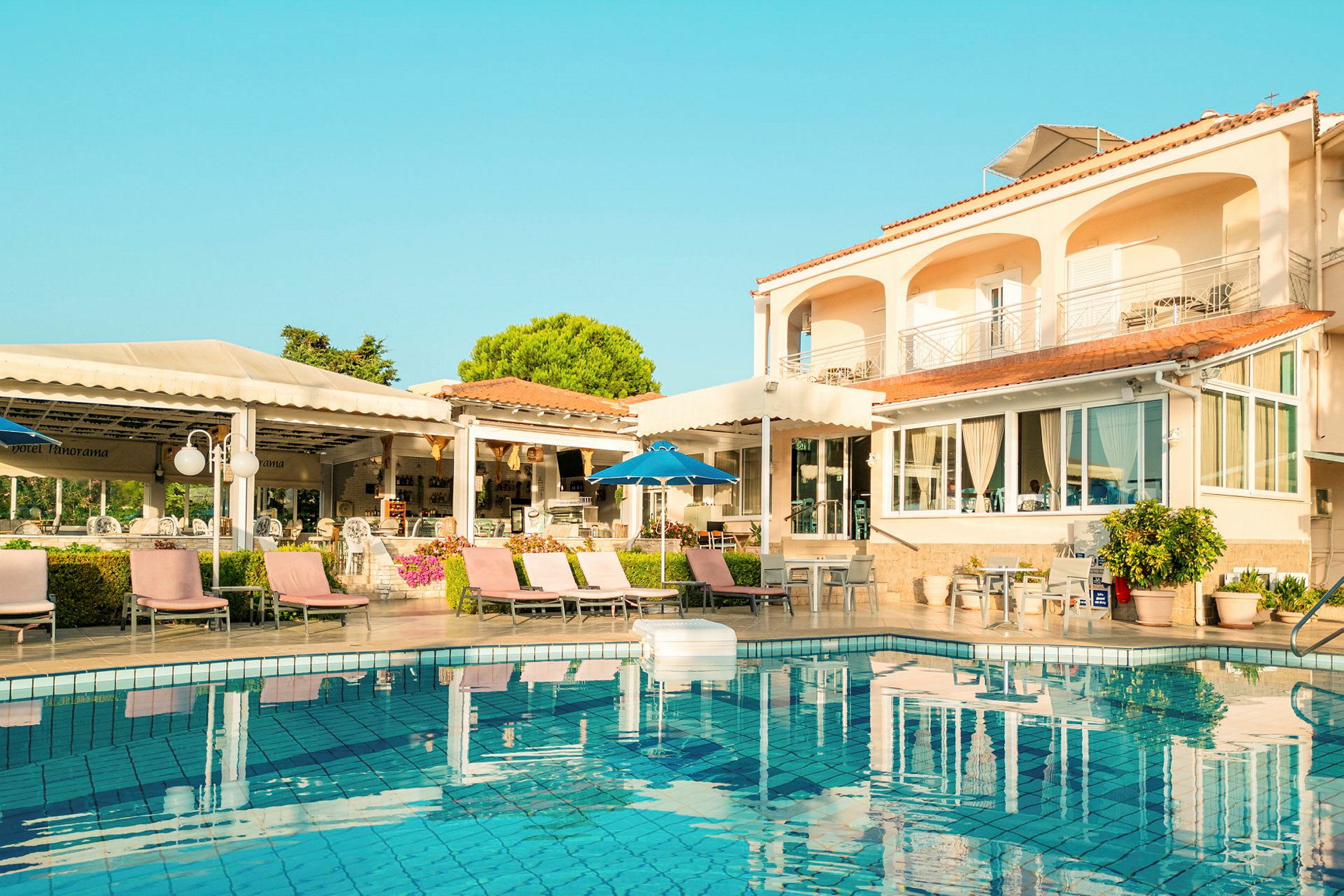 Udendørs område med hotel, swimmingpool og liggestole. (AI-genereret tekst)