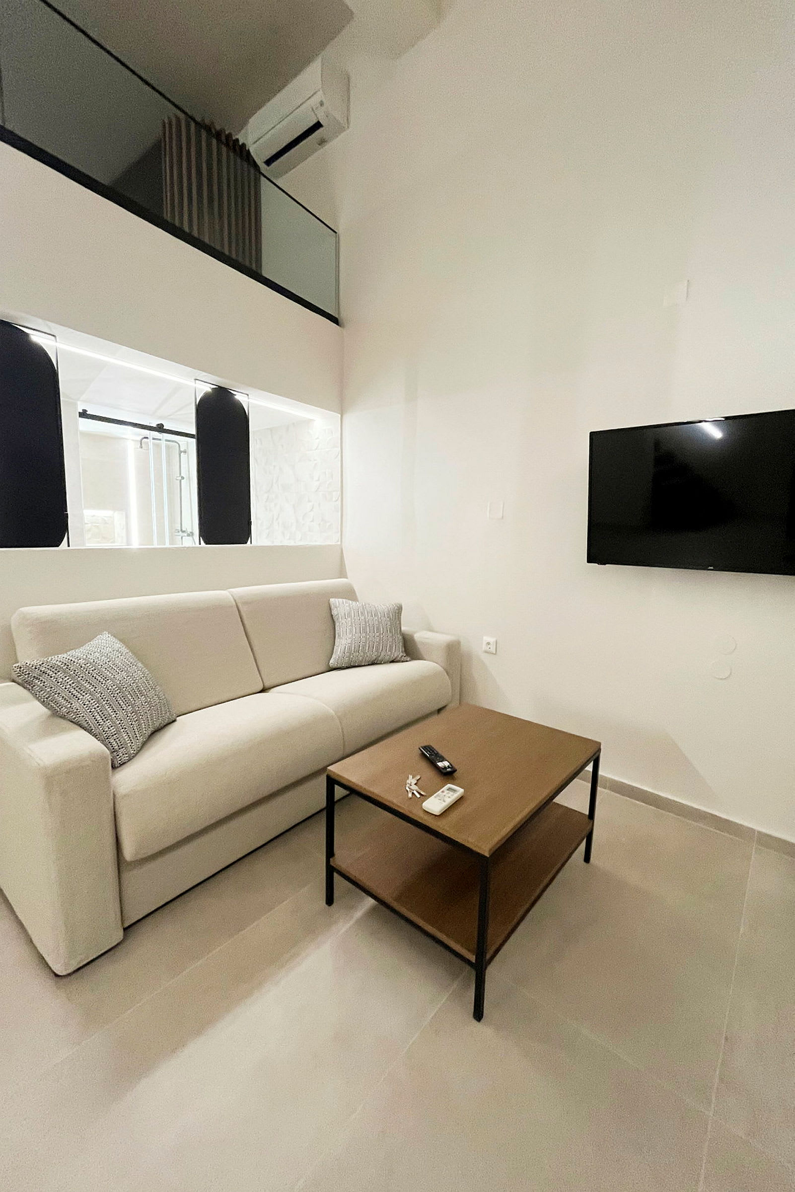 Billede af et moderne rum med en beige sofa, et træbord og et vægmonteret TV. (AI-genereret tekst)