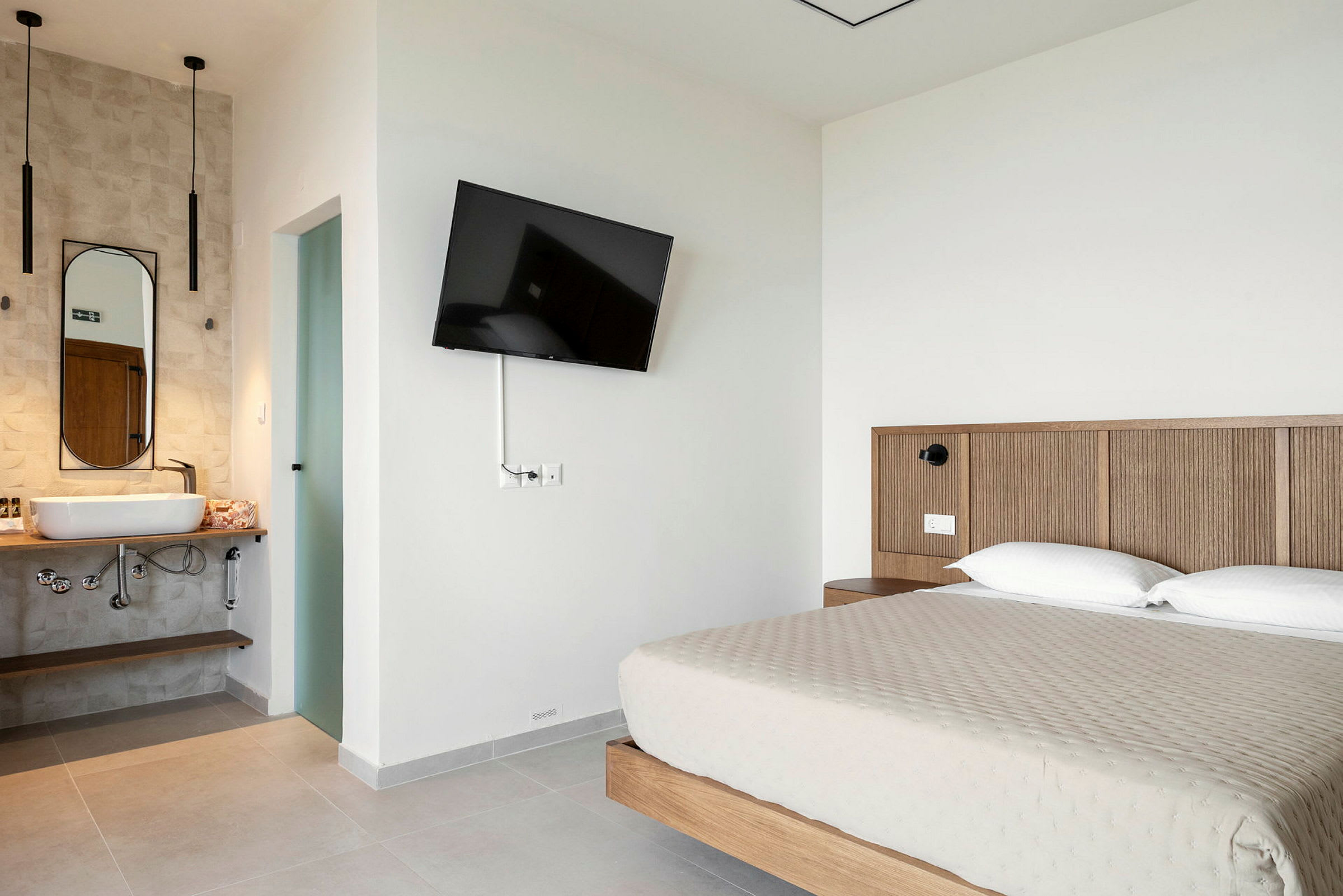 Hotelværelse med en dobbeltseng, vægmonteret TV og et åbent badeværelse. (AI-genereret tekst)