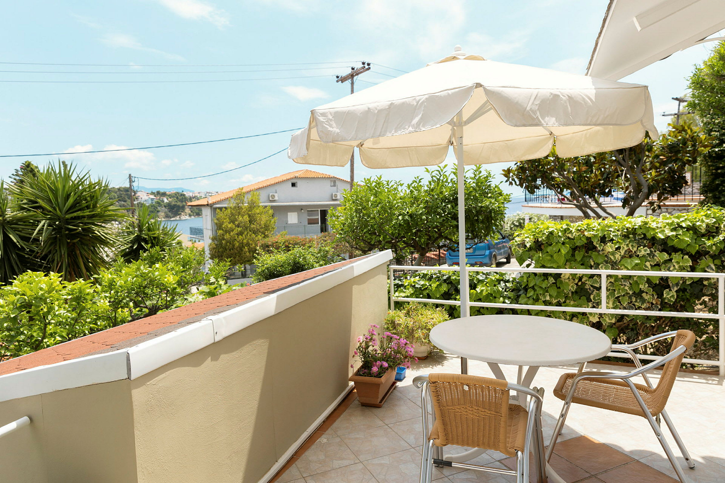 En terrasse med bord, stole og parasol, omgivet af grønt. (AI-genereret tekst)