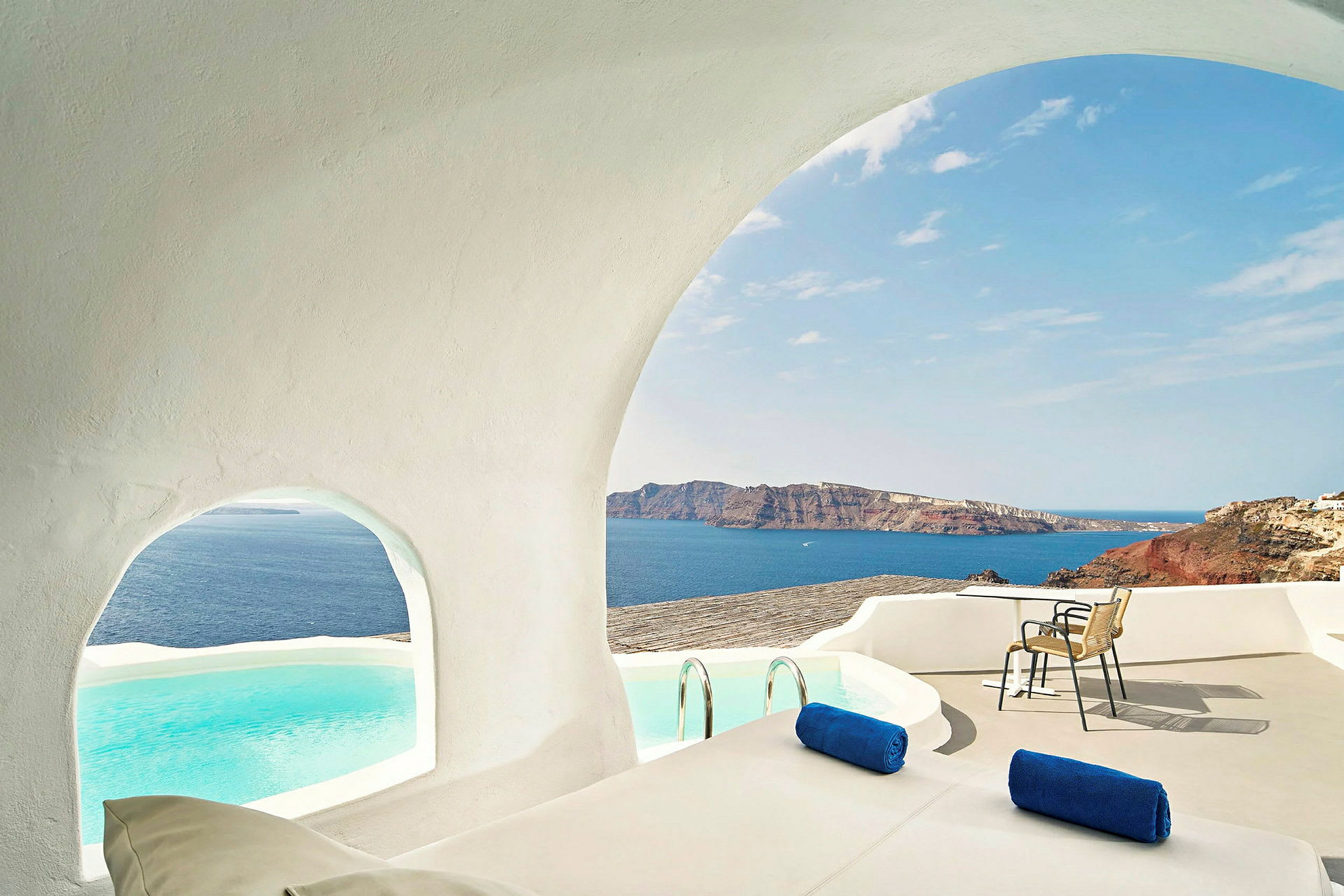 En terrasse med hvid arkitektur, udsigt over havet og en pool. (AI-genereret tekst)