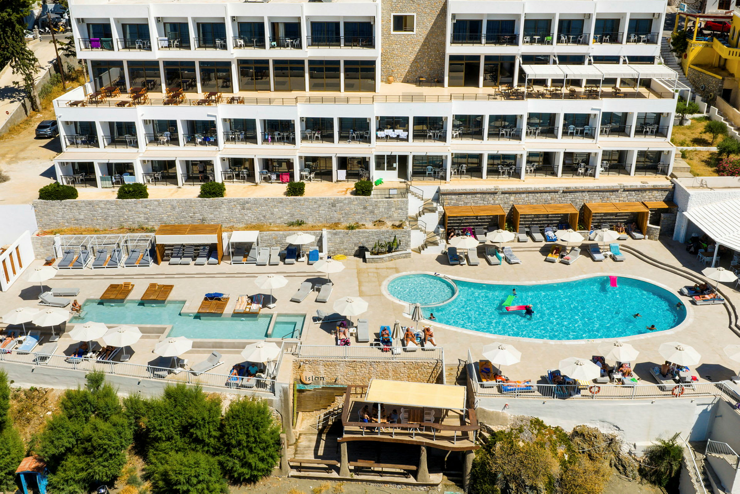 Luftfoto af hotelområde med pool og liggestole. (AI-genereret tekst)
