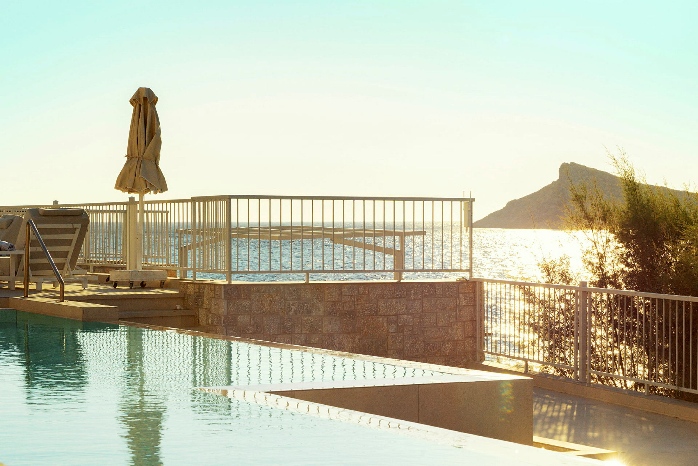 En pool med udsigt over havet og en solrig himmel. (AI-genereret tekst)