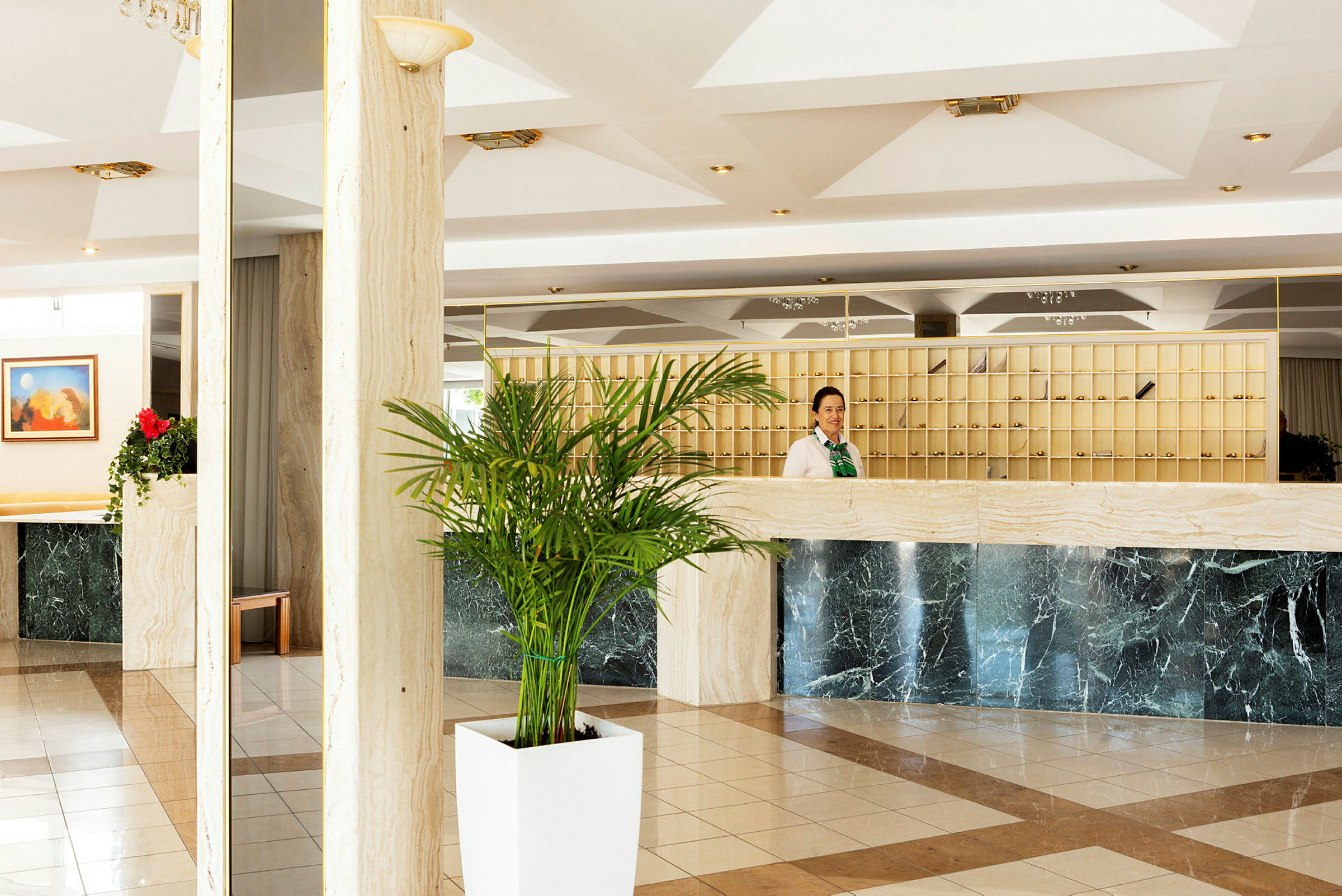 Hotelreception med en marmordisk og grønne planter. (AI-genereret tekst)