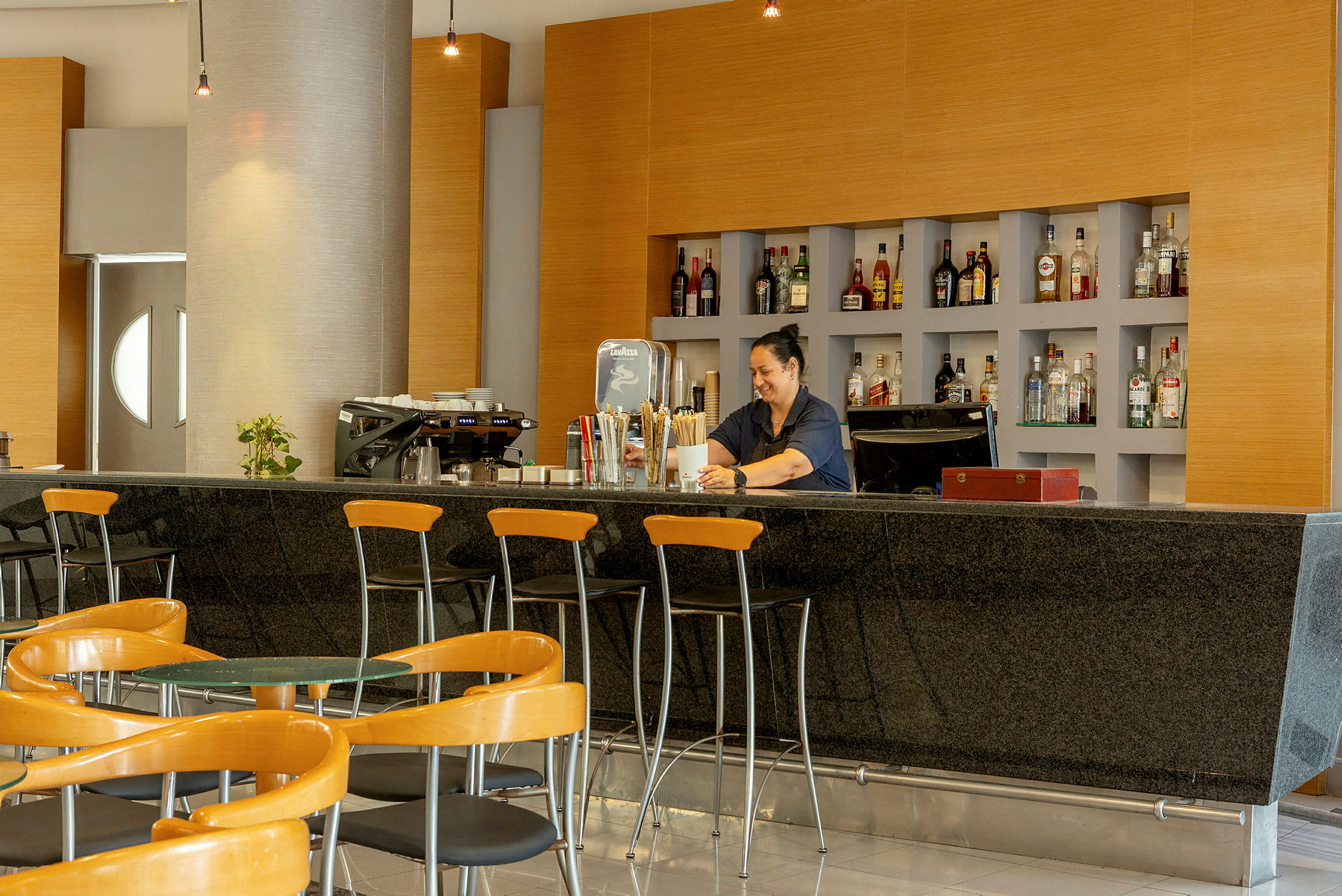 En hotelbar med siddeområde og hylder fyldt med flasker. (AI-genereret tekst)