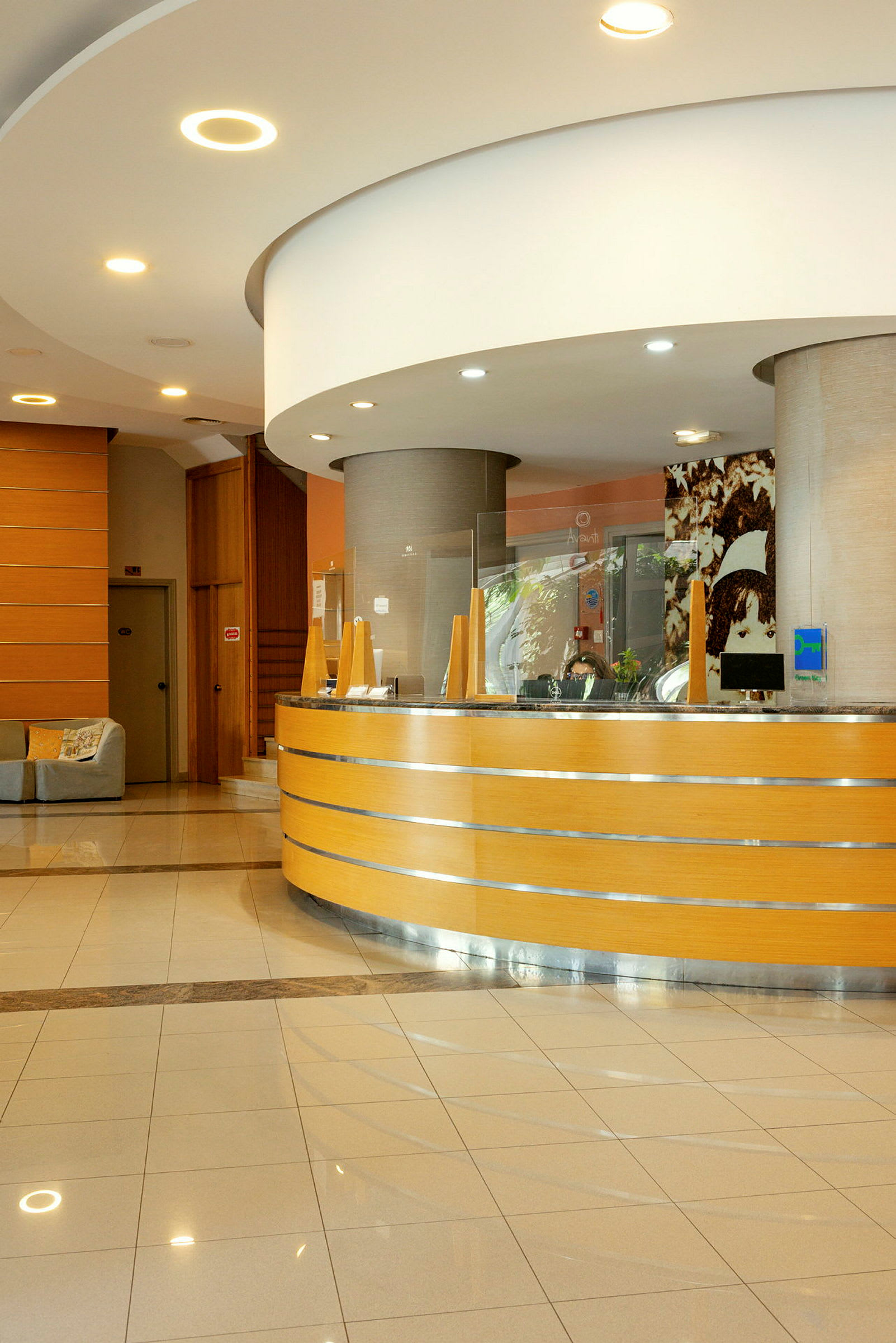 En receptionsskranke i træ med dekorativ belysning og glasdetaljer i en hotellobby. (AI-genereret tekst)