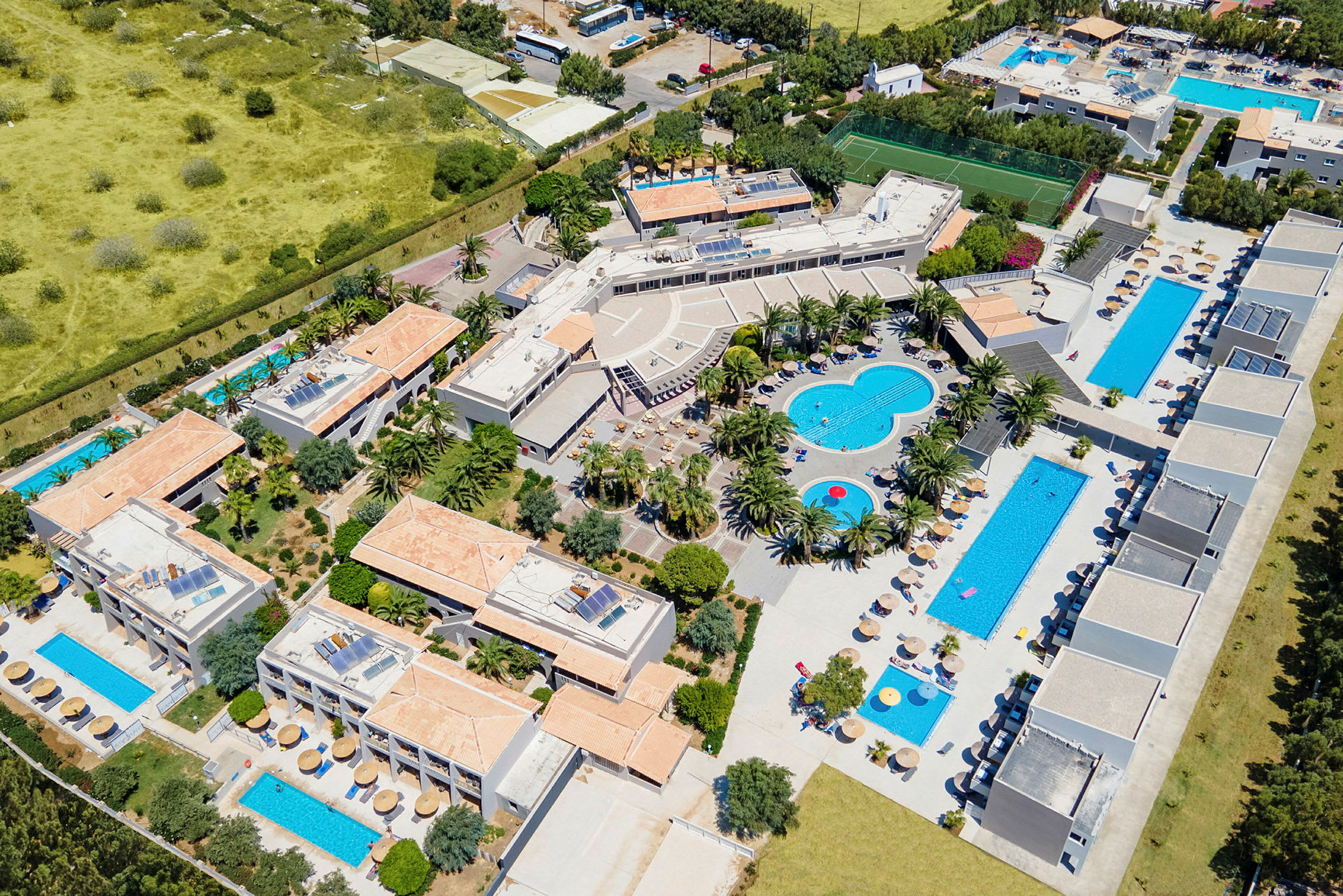 Luftfoto af et feriested med swimmingpools, bygninger og palmer. (AI-genereret tekst)