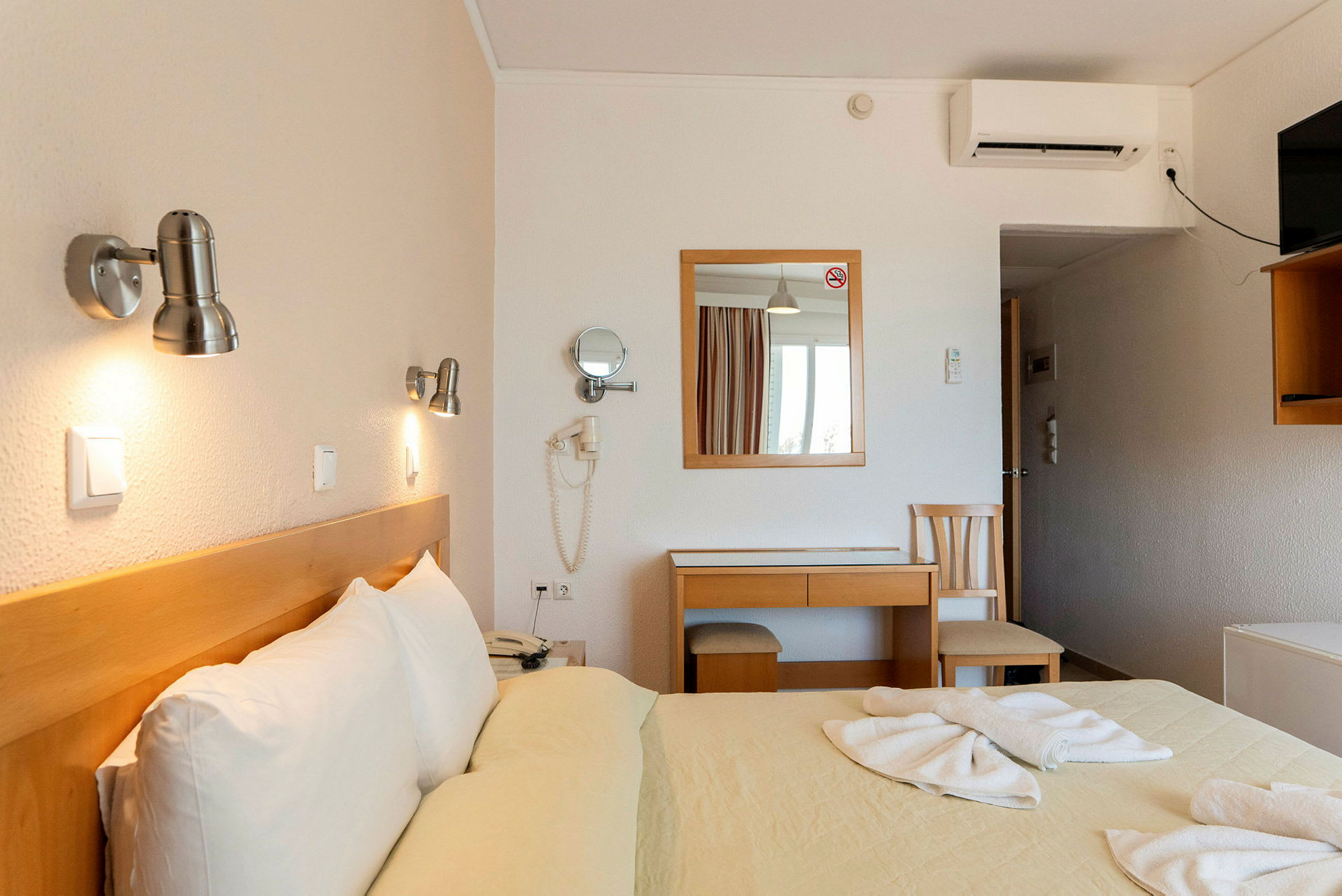 Hotelværelse med dobbeltseng og skrivebord. (AI-genereret tekst)
