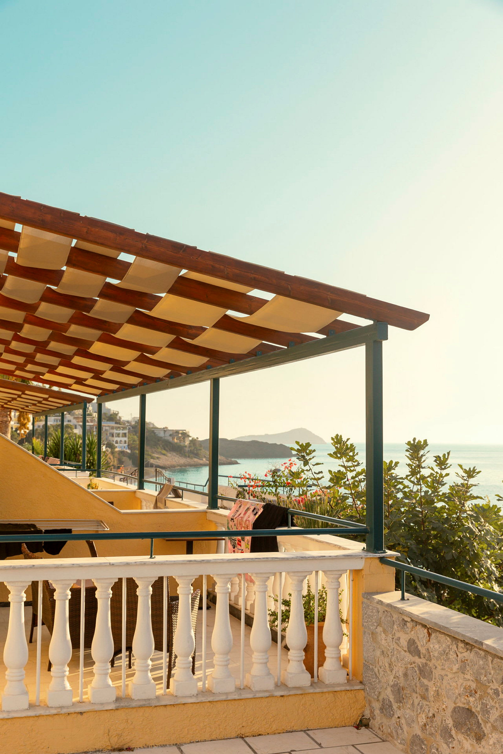Udsigt fra en terrasse med pergola mod havet. (AI-genereret tekst)