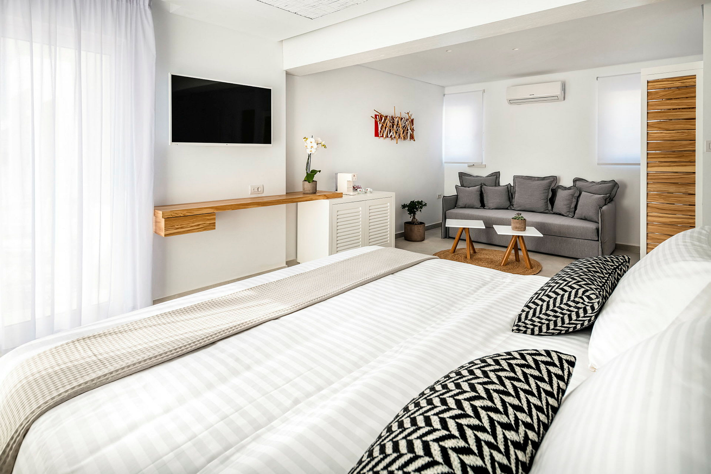 Et lyst, moderne hotelværelse med seng, sofa og TV. (AI-genereret tekst)