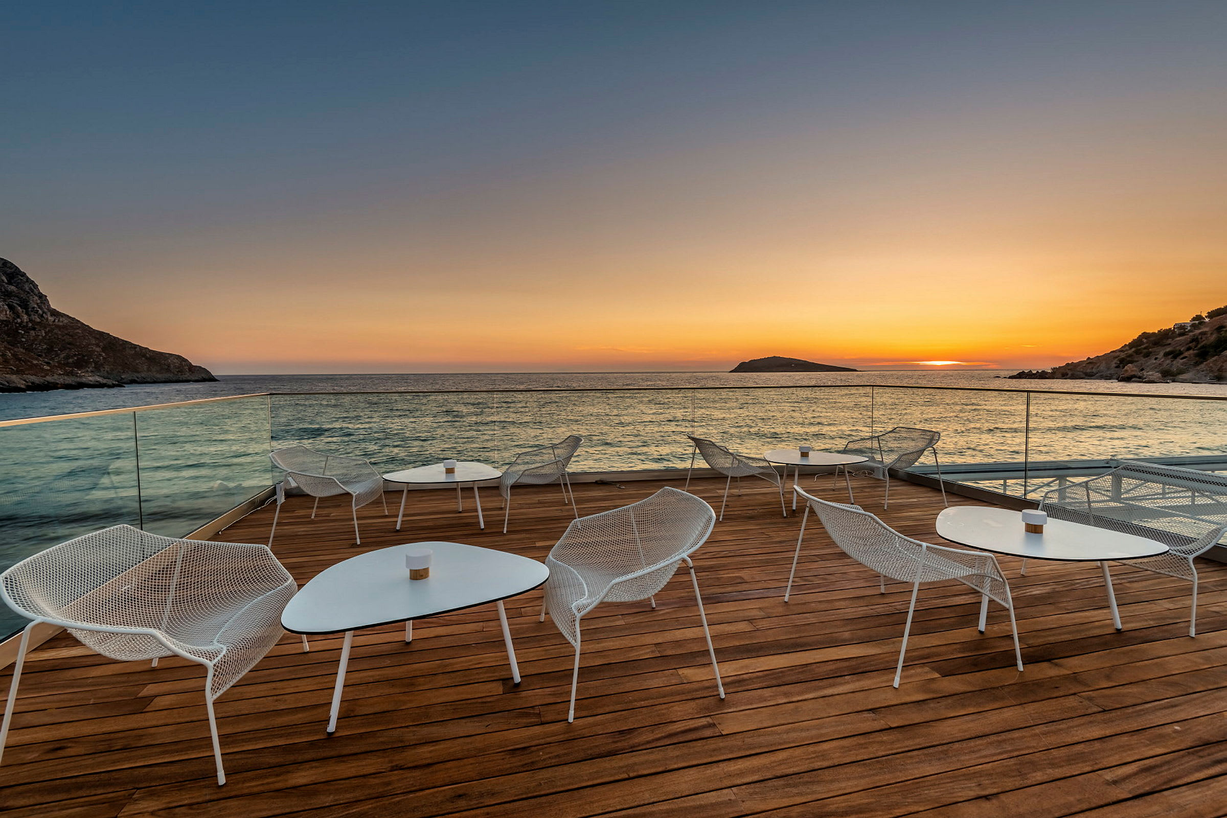En terrasse med siddearrangementer ved havet ved solnedgang. (AI-genereret tekst)