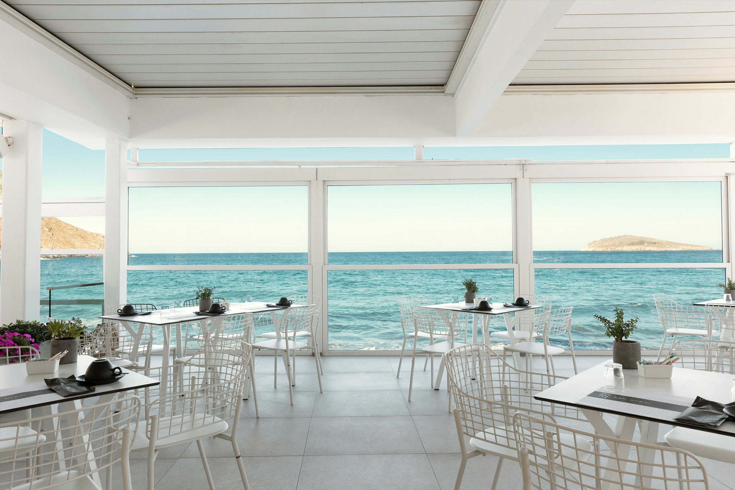 Restaurant med udsigt over havet gennem store vinduer. (AI-genereret tekst)