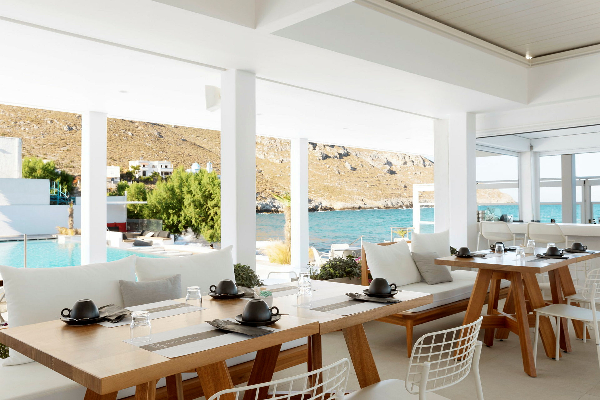 En åben restaurant med udsigt over en pool og havet bagved. (AI-genereret tekst)