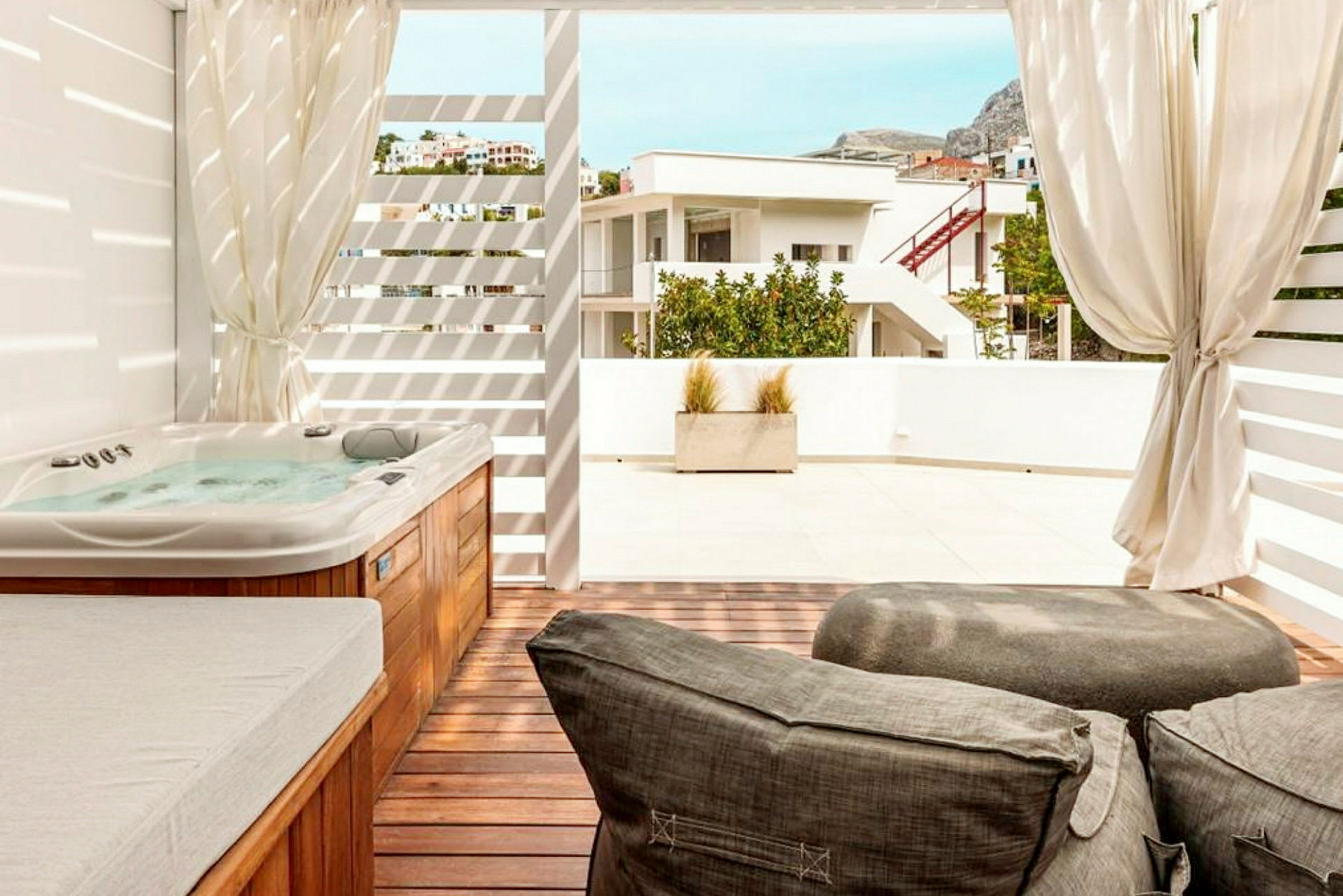 Billedet viser en terrasse med en jacuzzi, liggestole og udsigt til nabobygningen. (AI-genereret tekst)