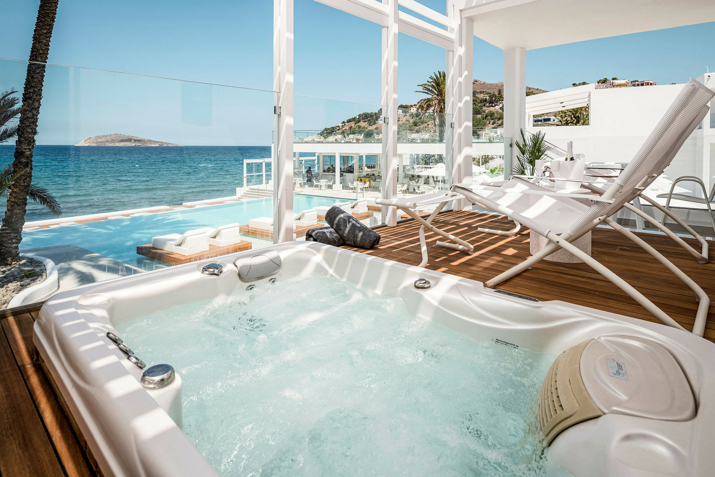 Jacuzzi på en terrasse med udsigt over havet og en pool. (AI-genereret tekst)