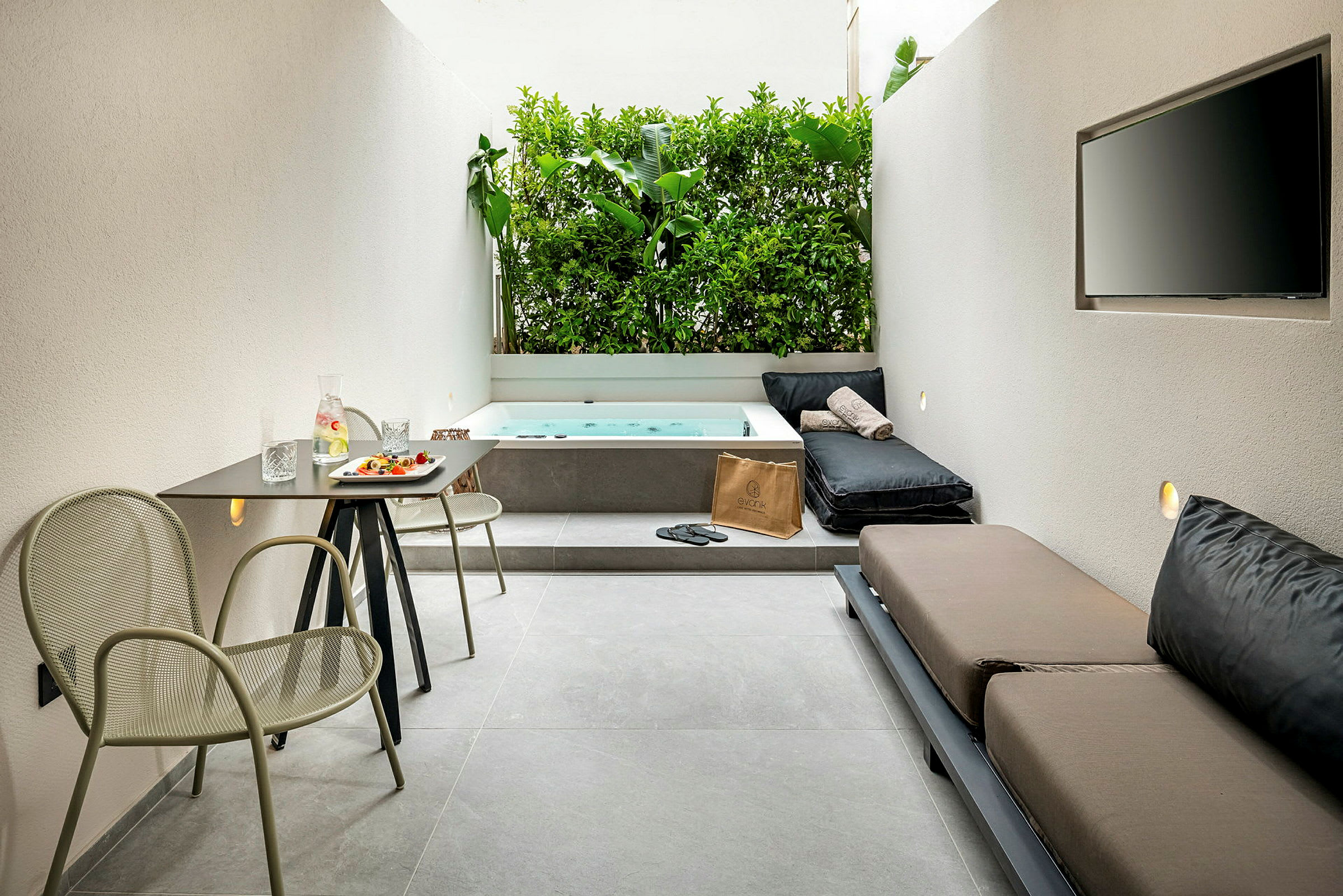 En moderne terrasse med bord, stole, sofa, jacuzzi og grøn væg. (AI-genereret tekst)