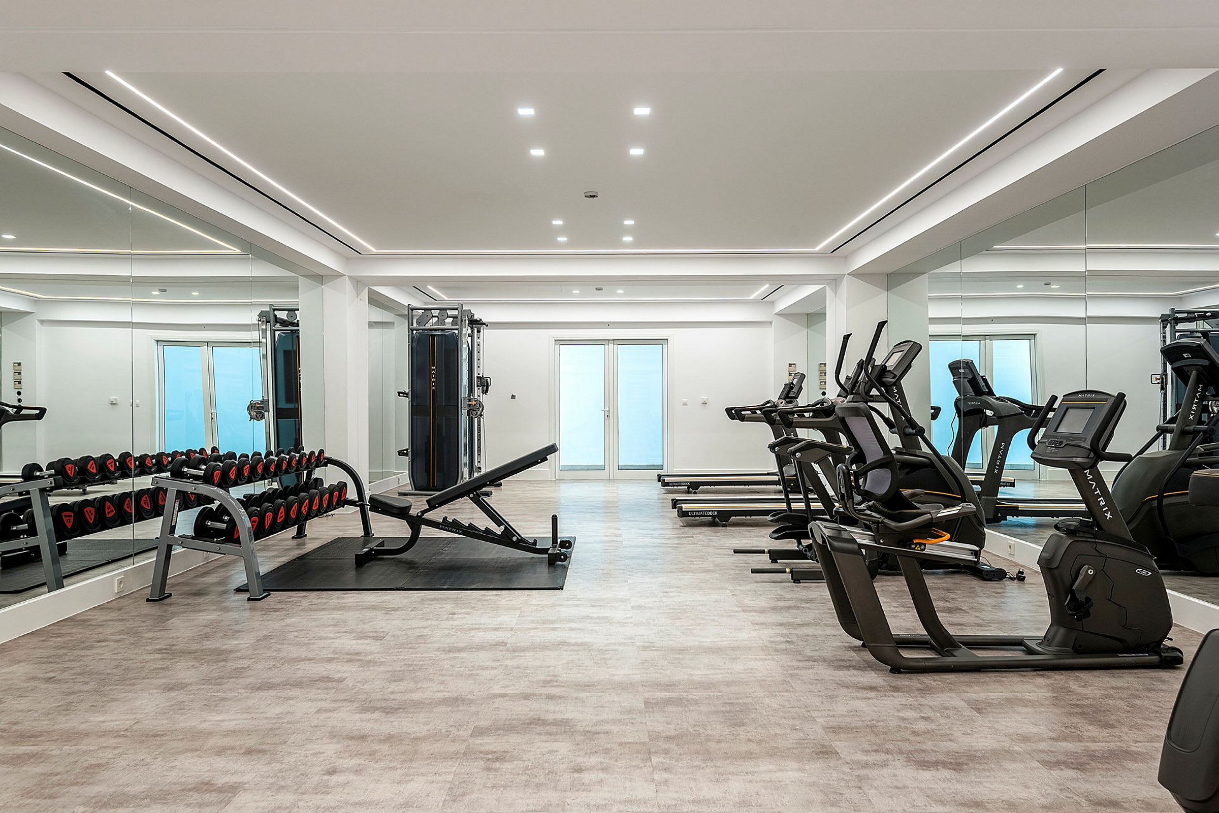 Et moderne fitnesscenter med træningsmaskiner, vægte og spejle. (AI-genereret tekst)