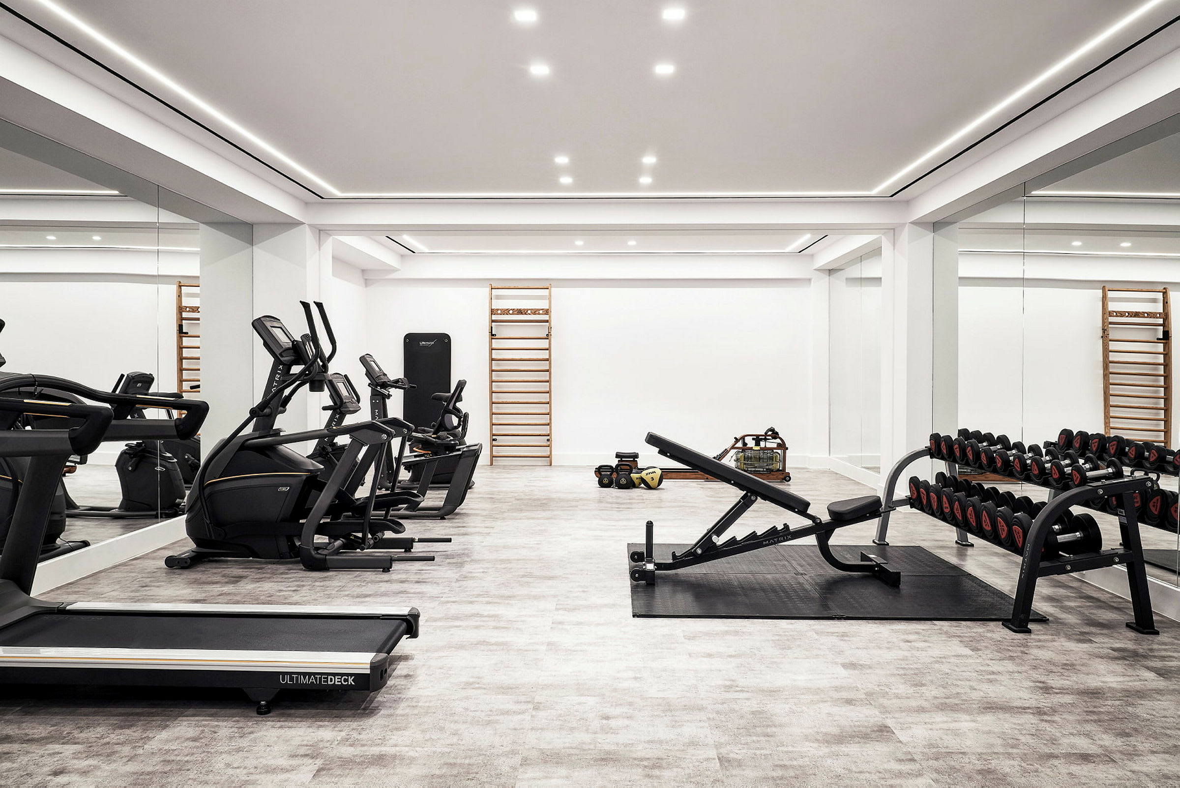 Fitnesscenter med træningsudstyr, herunder løbebånd, motionscykler, håndvægte og bænkpres. (AI-genereret tekst)