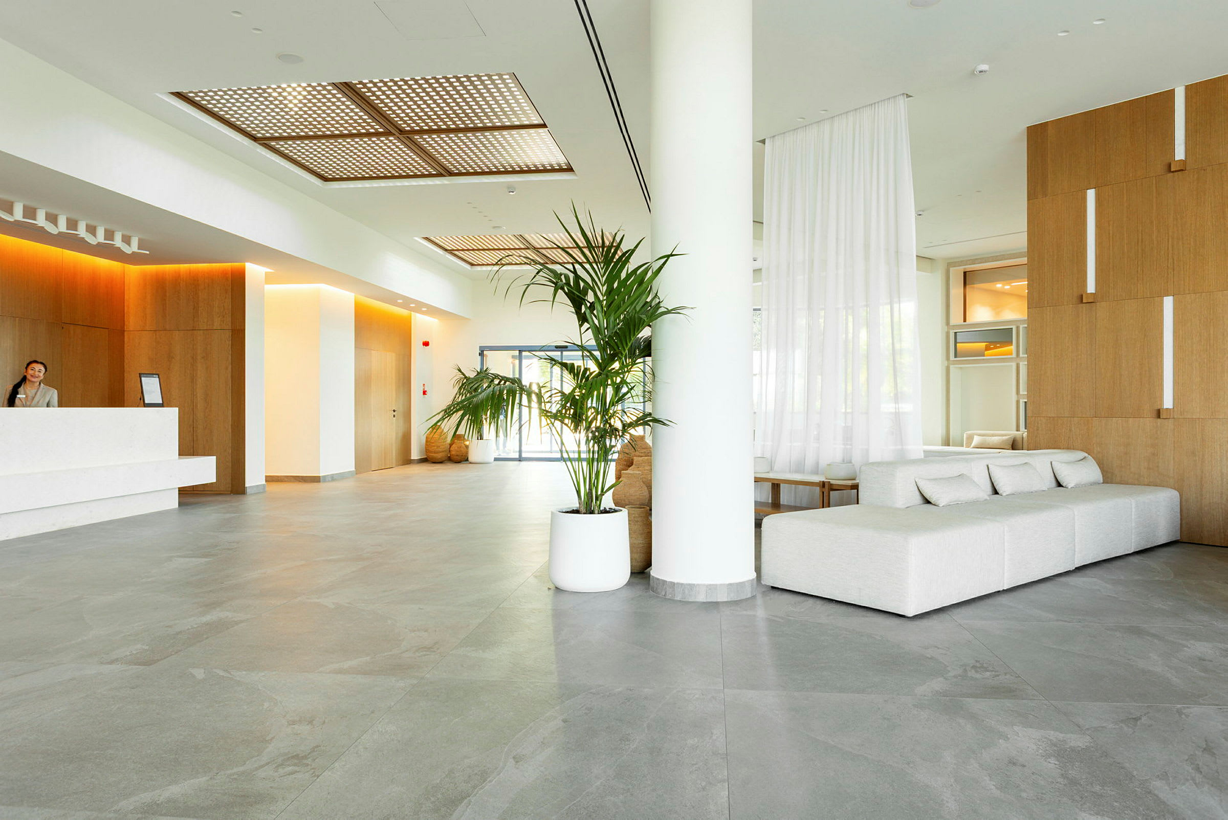 Inde i en moderne hotellobby med en reception, sofaer og planter. (AI-genereret tekst)