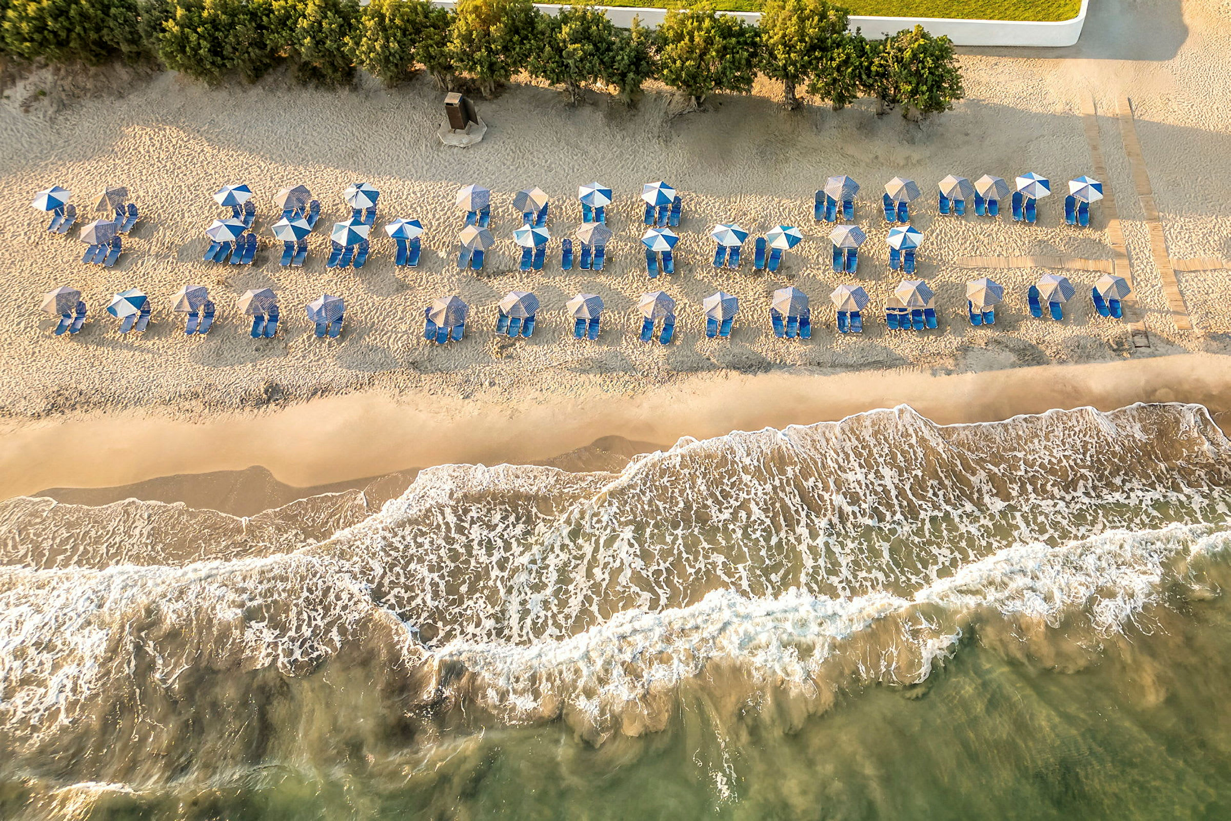 Strand med parasoller og solvogne set ovenfra. (AI-genereret tekst)